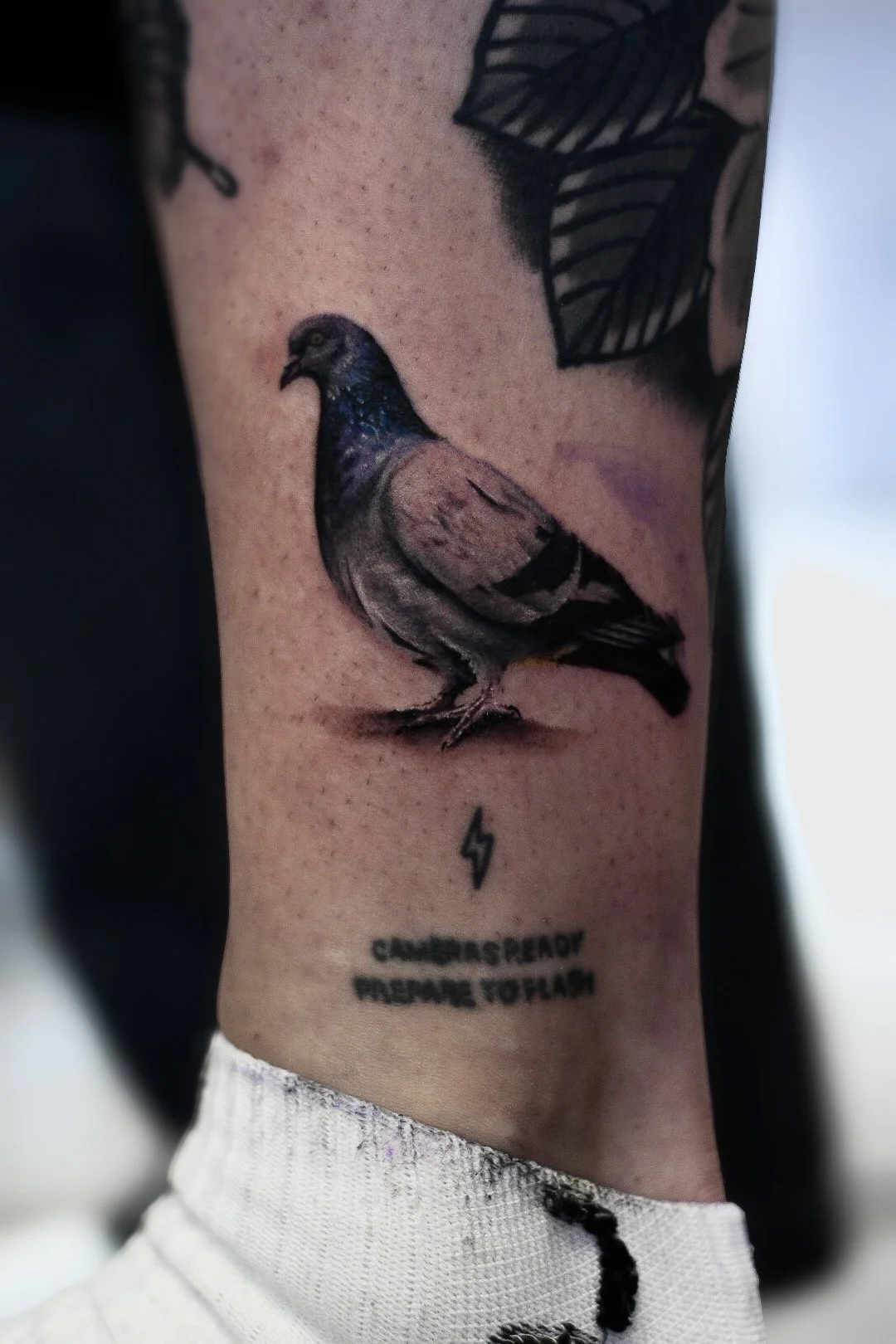 Tattoo of a detailed bird, likely a sparrow, with text below that reads 'CHARGERS READY PRESENCE TO FLASH', along with a small lightning bolt symbol.