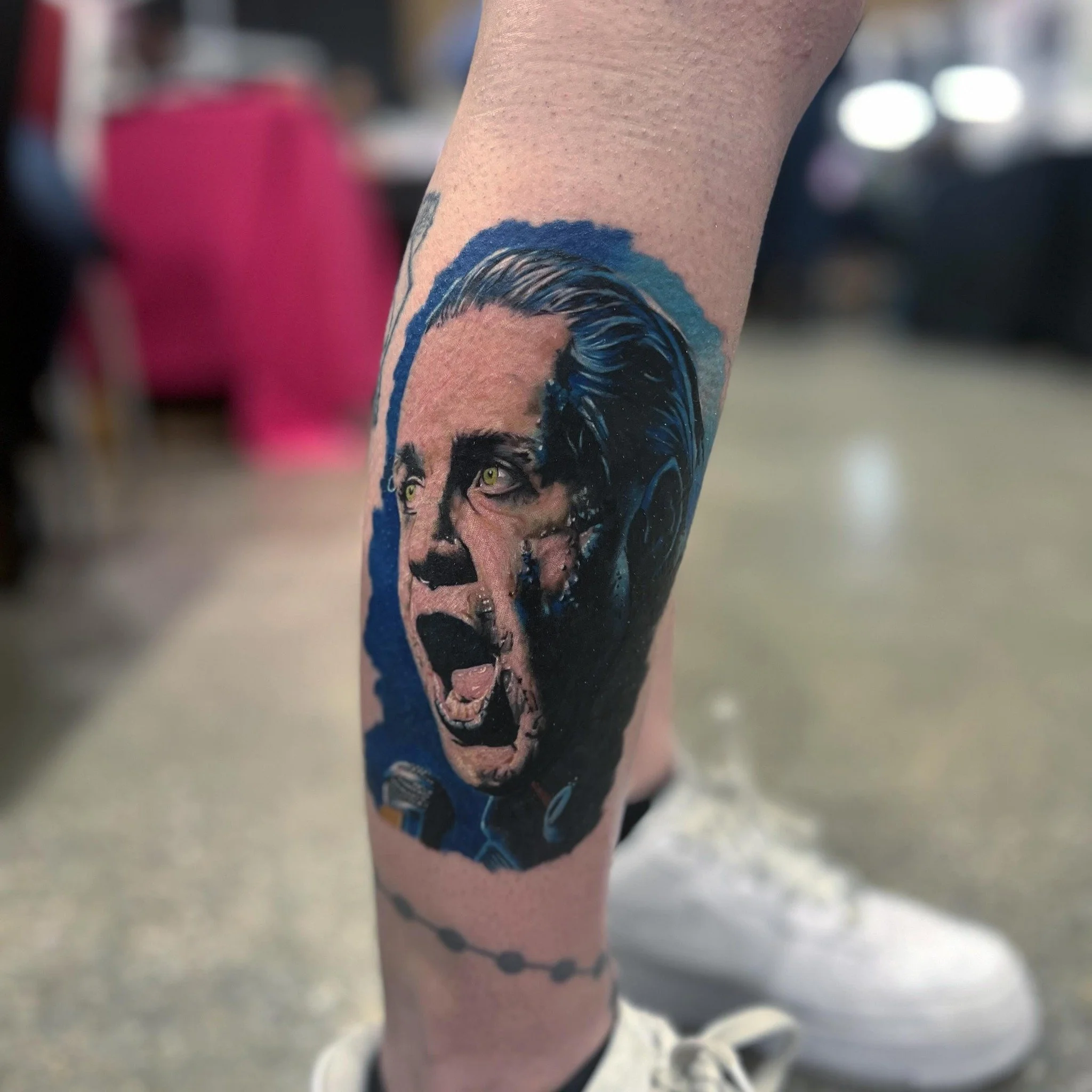 Tattoo of a woman with an intense facial expression and blonde hair, depicted on a person's leg.