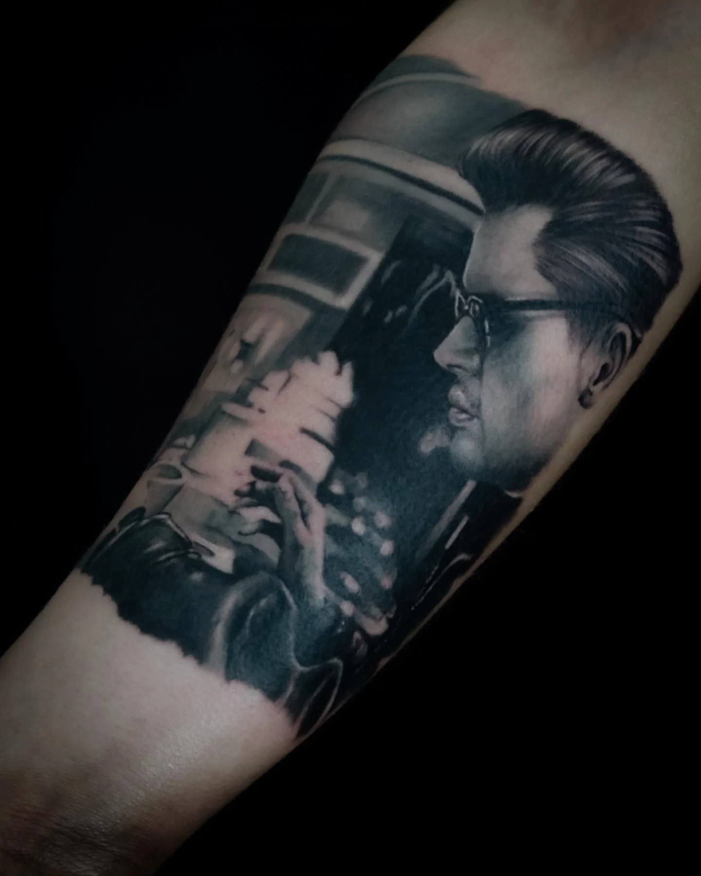 Black and gray photorealistic tattoo of a man with styled hair and glasses holding a cigarette.