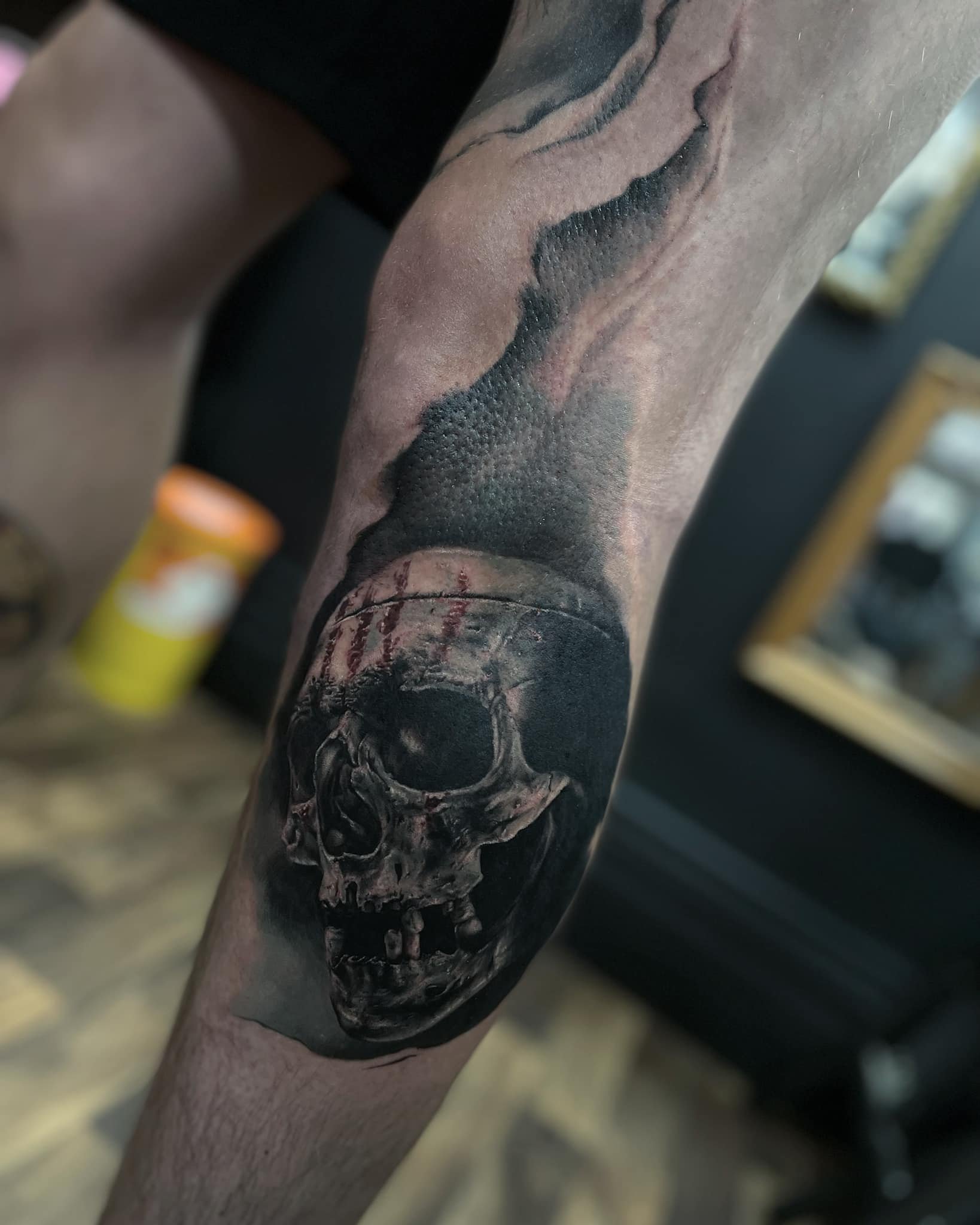 Tattoo of a human skull on a person's forearm, with a snake-like figure above it.