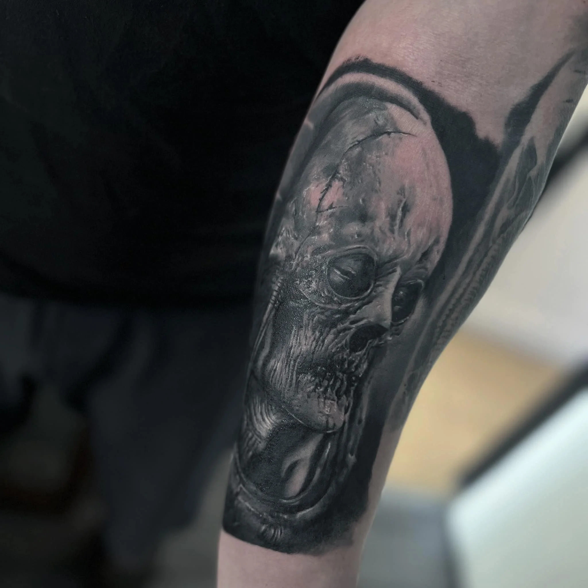 Black and gray tattoo of a screaming skull on a person's forearm.