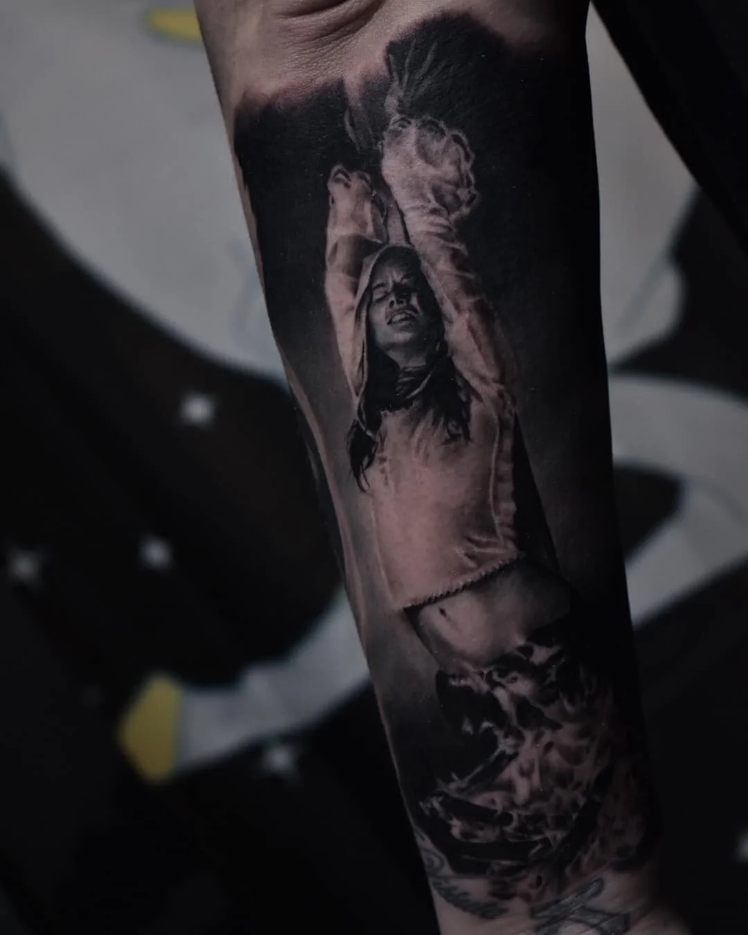 Black and grey tattoo of a woman with her arms raised, wearing a jacket, with a large animal, possibly a dog or wolf, above her head.