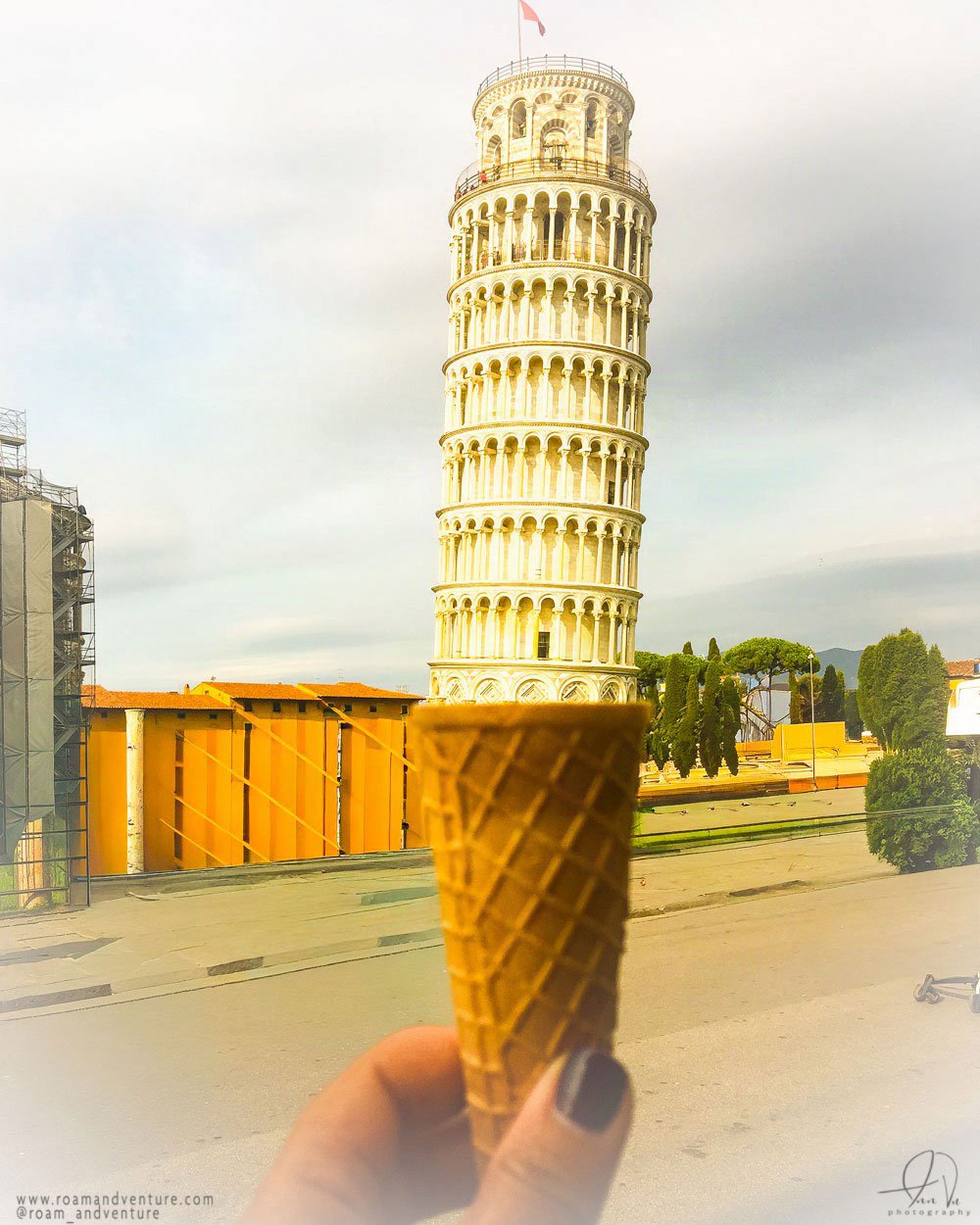 Person holding an ice cream cone in front of the Leaning Tower of Pisa in Italy.