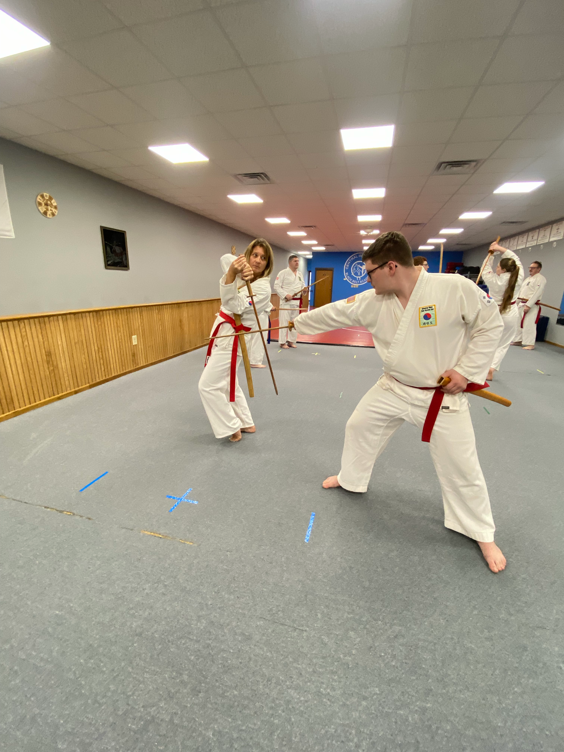 Martial artists practicing techniques in a dojo with cones marked on the floor.