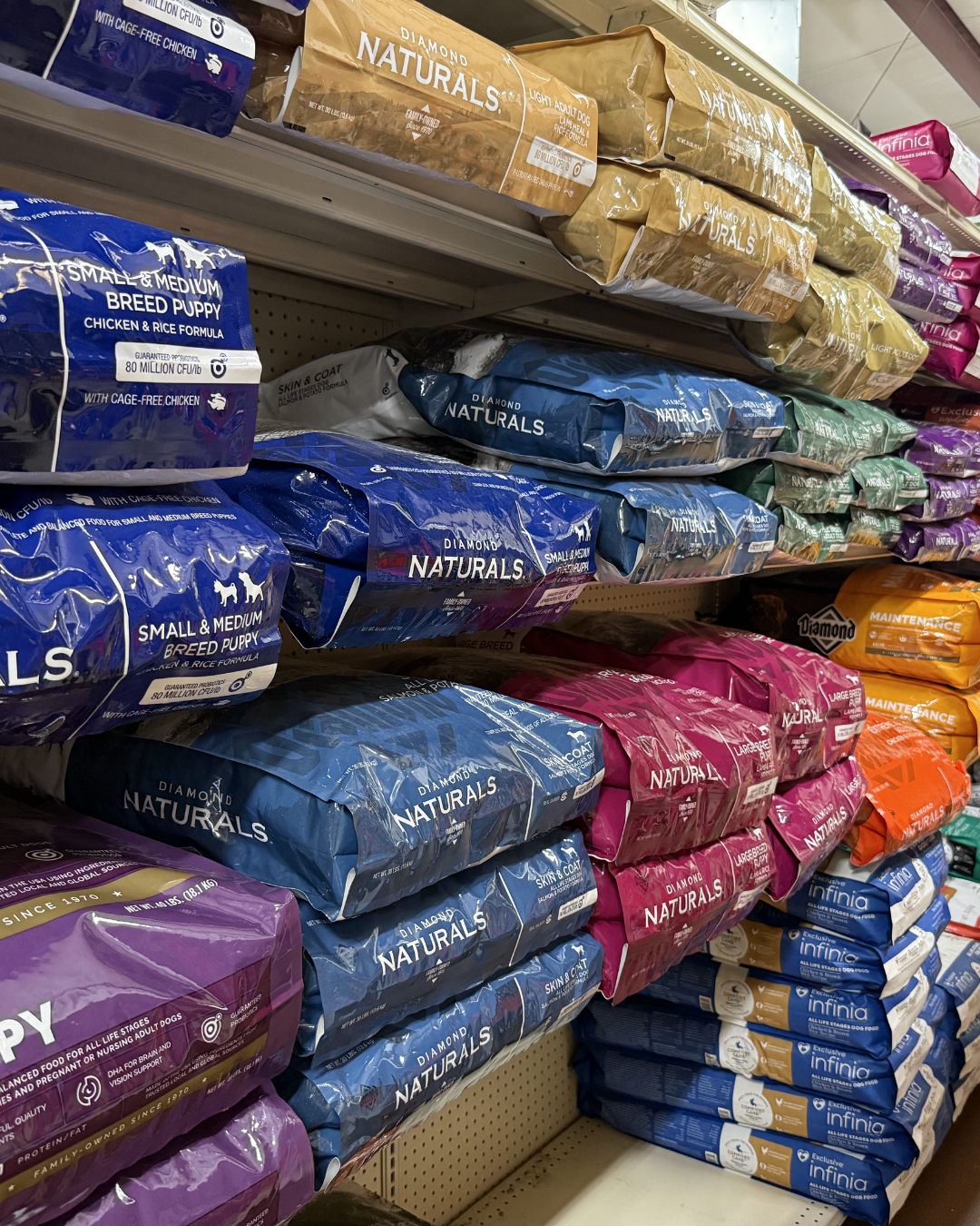 Shelves stocked with bags of Diamond Naturals dog food in various sizes and flavors at a pet store.