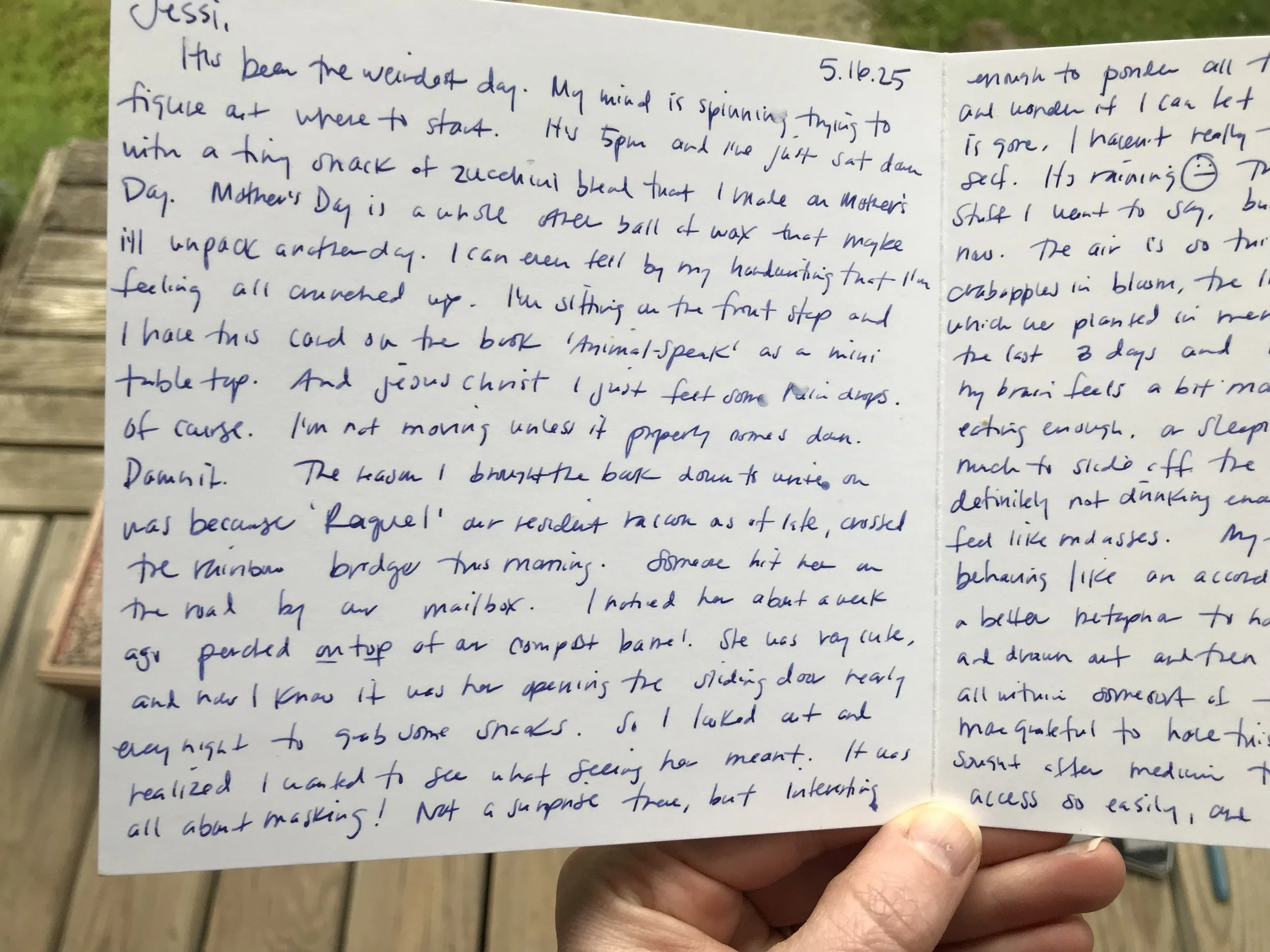 Close-up of a handwritten letter on white paper, with the date 5.16.25 visible in the top right corner, being held by a person's hand over a wooden surface.