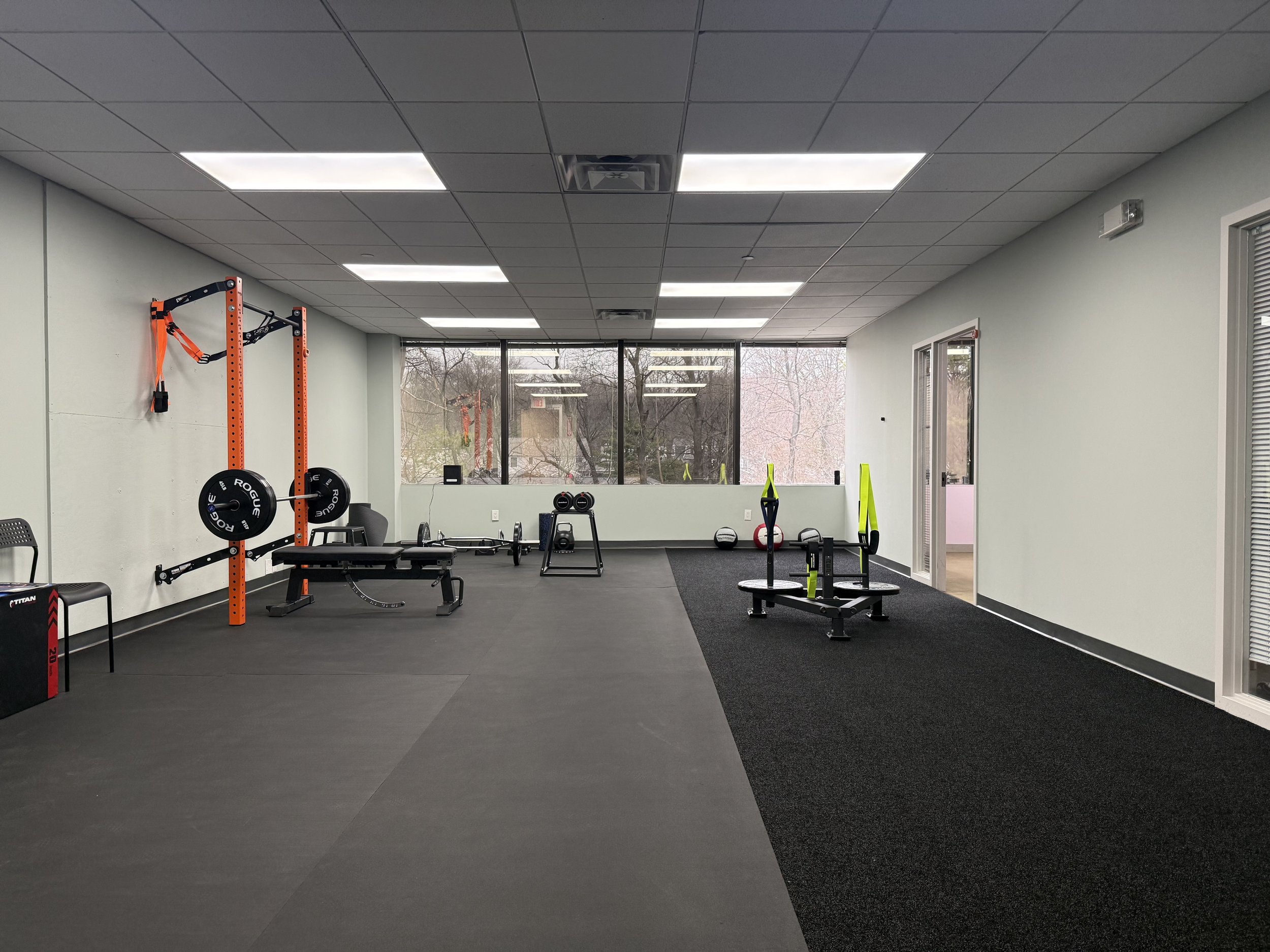 “Strength training area inside First Principles PT clinic with weights, turf flooring, and rehabilitation equipment”