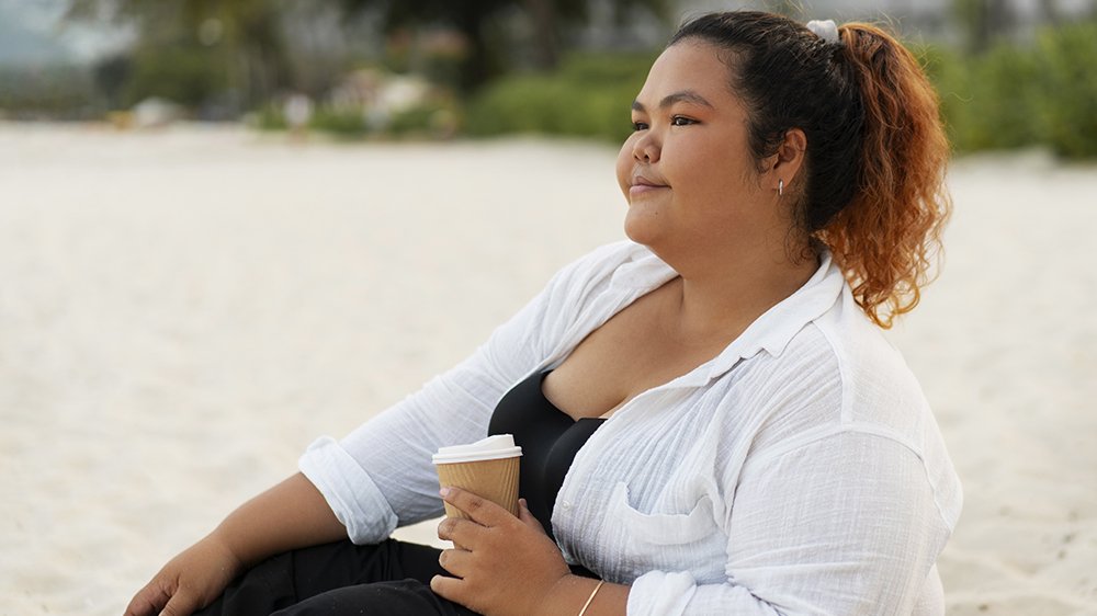 Adult woman sitting thoughtfully outdoors, representing personal growth
