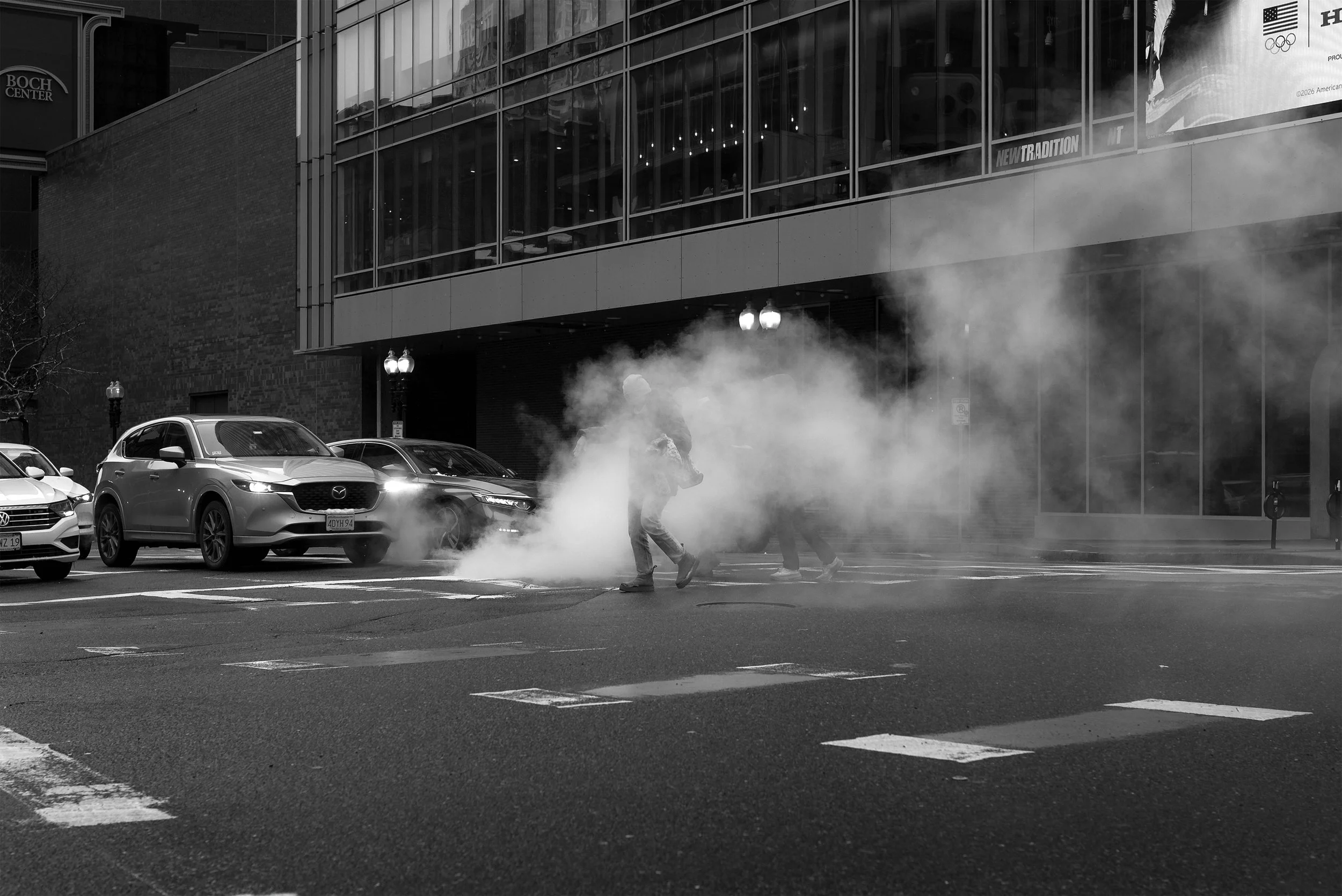 A person walking through the steam rising up from a manhole cover