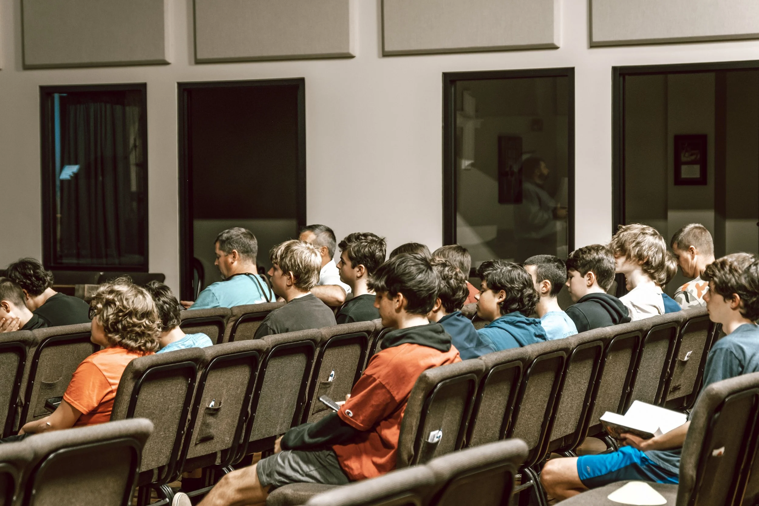 Group of people seated in a conference room, listening to a presentation.