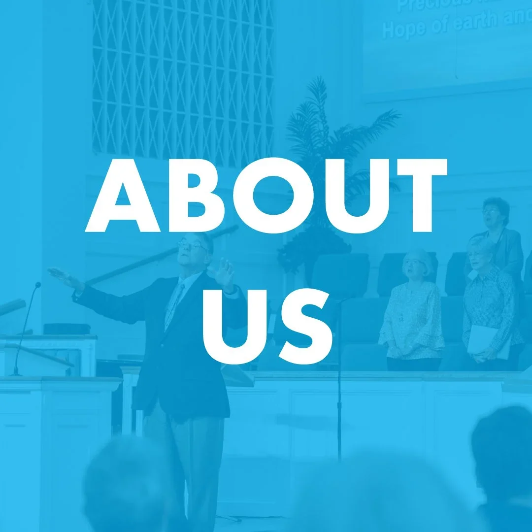 A group of people in a formal setting, with a man speaking at a podium, and a large sign reading 'ABOUT US' superimposed on the image.