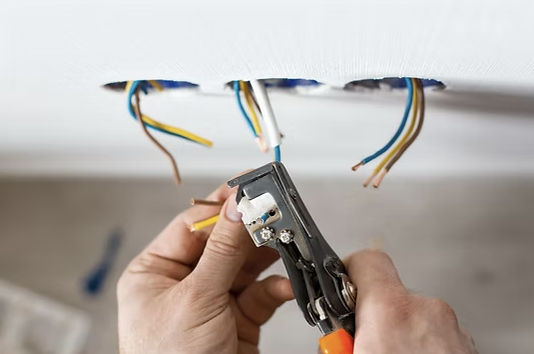 Person cutting electrical wires with wire cutters.