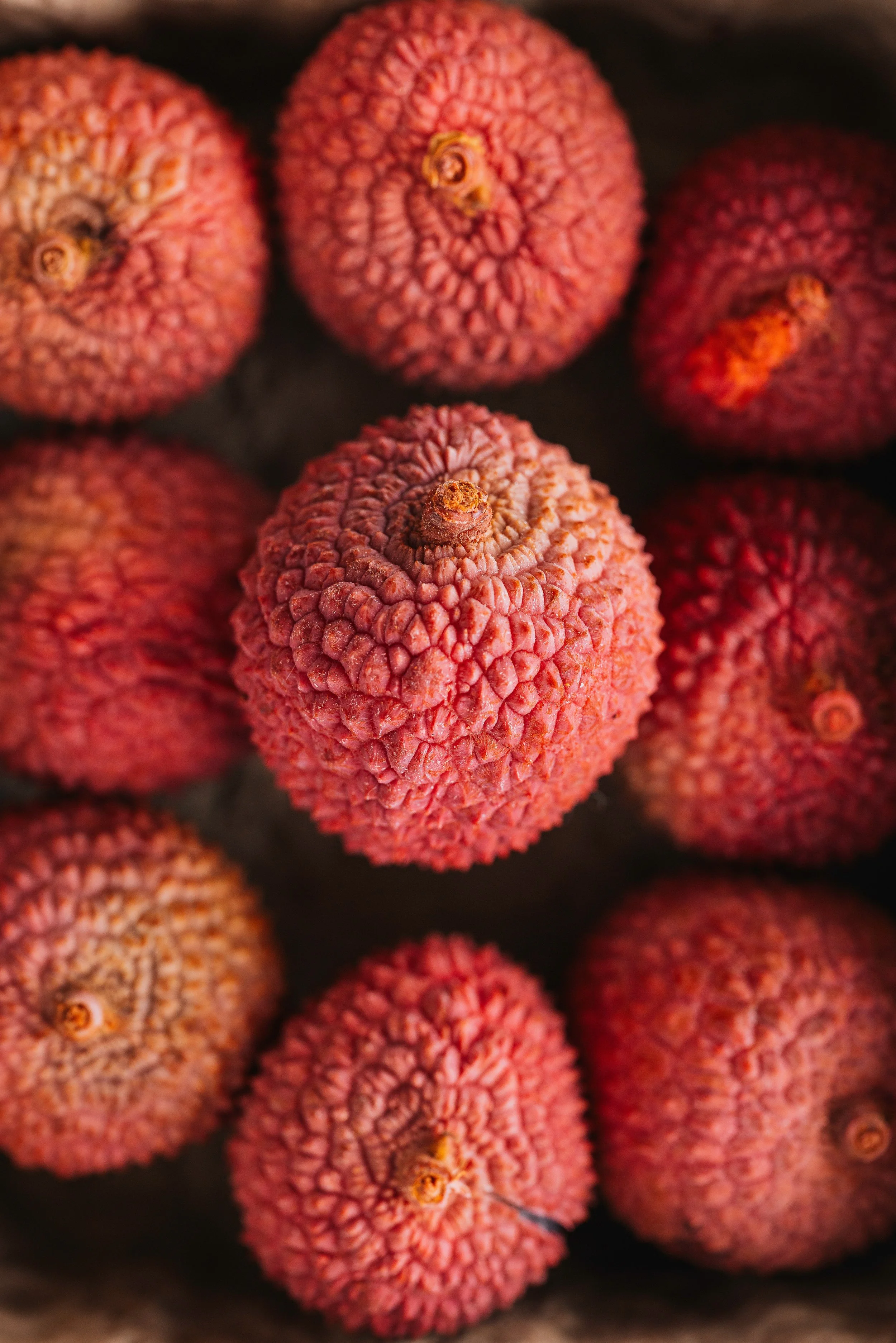 Close-up of several lychee fruits with rough, textured, pinkish-red skin.