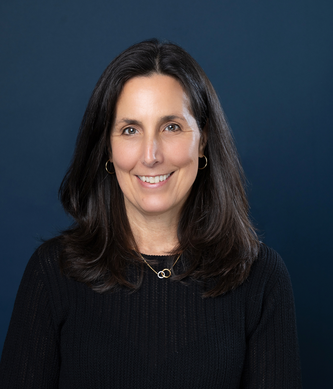 Miranda P. Siemasko smiling in front of a blue background.