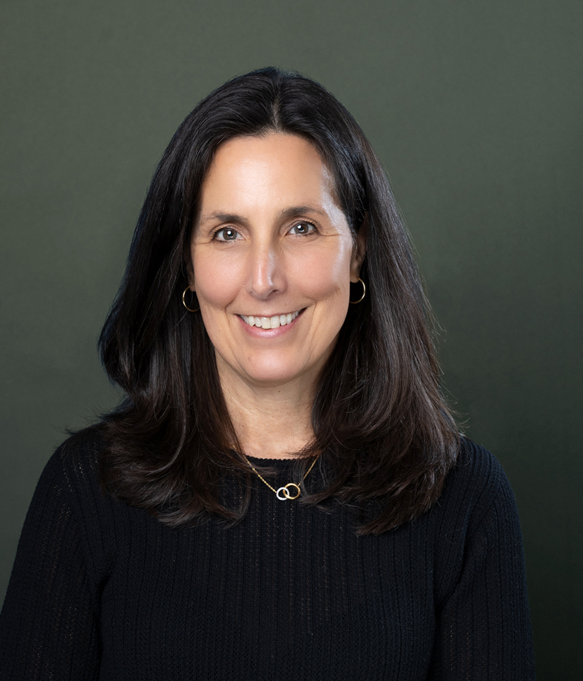 Miranda P. Siemasko smiling in front of a dark green background.