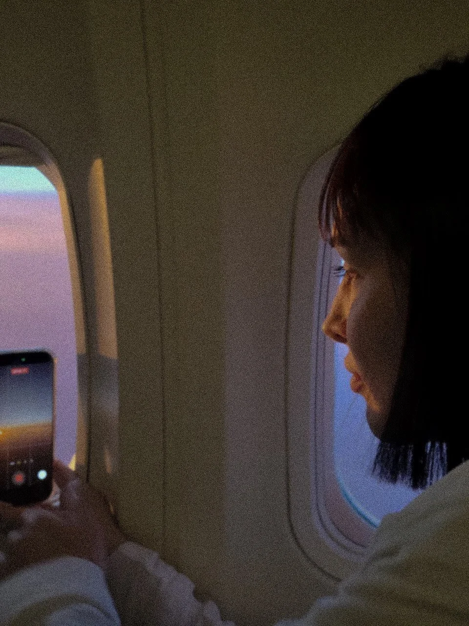 Larissa Mara Vale observando a vista pela janela do avião durante viagem - Reflexão sobre perspectiva e estilo de vida.
