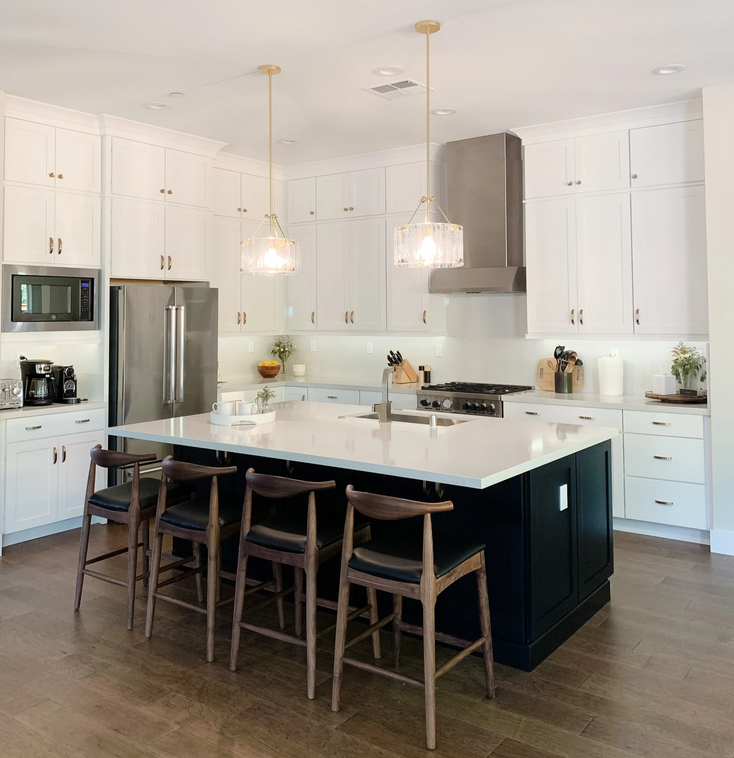 White modern kitchen with brass accents and glass pendants, wood counter stool--Casa Limones interior design