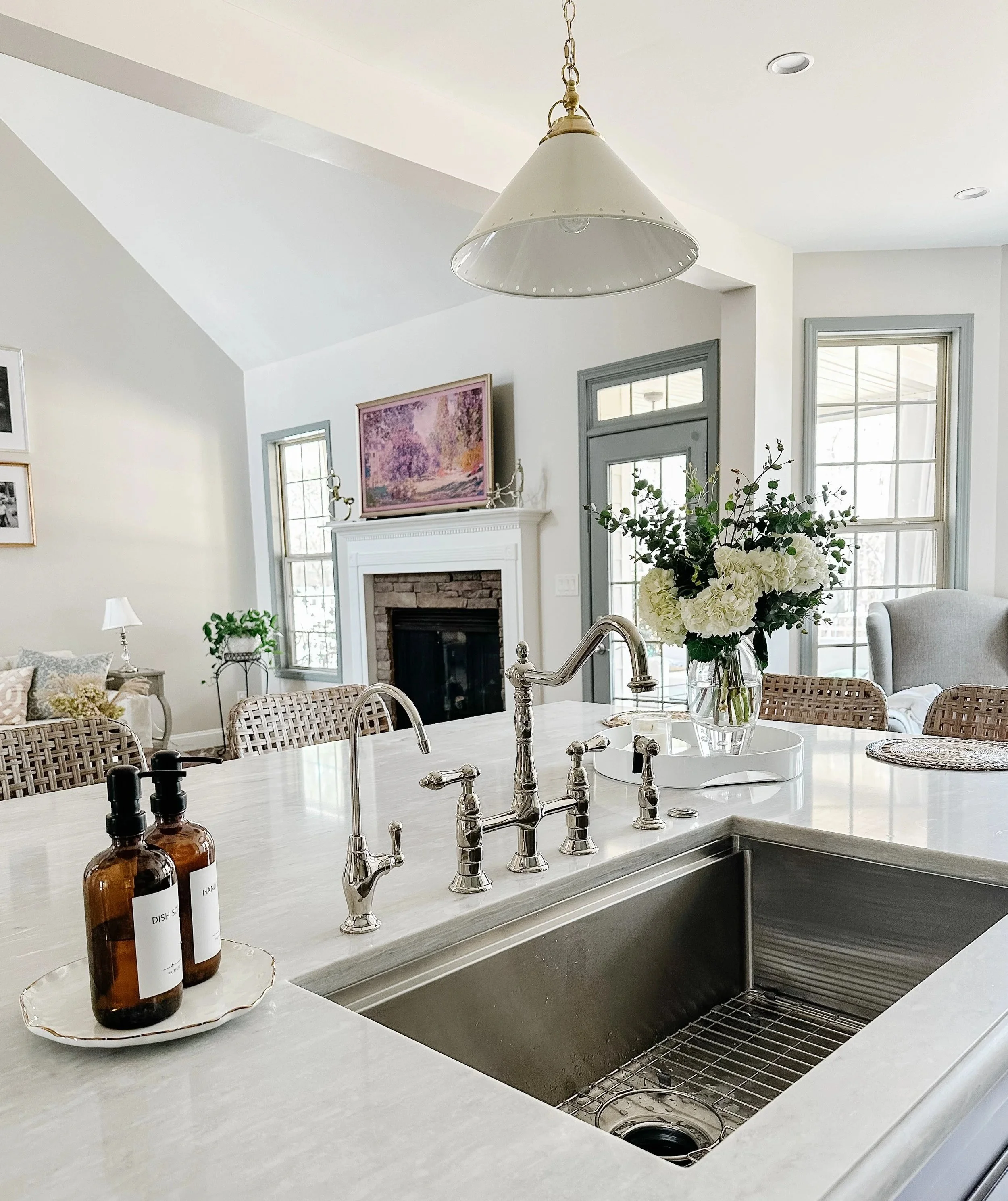 White quartz marble kitchen island with polished nickel faucet and brass pendants--Casa Limones interior design