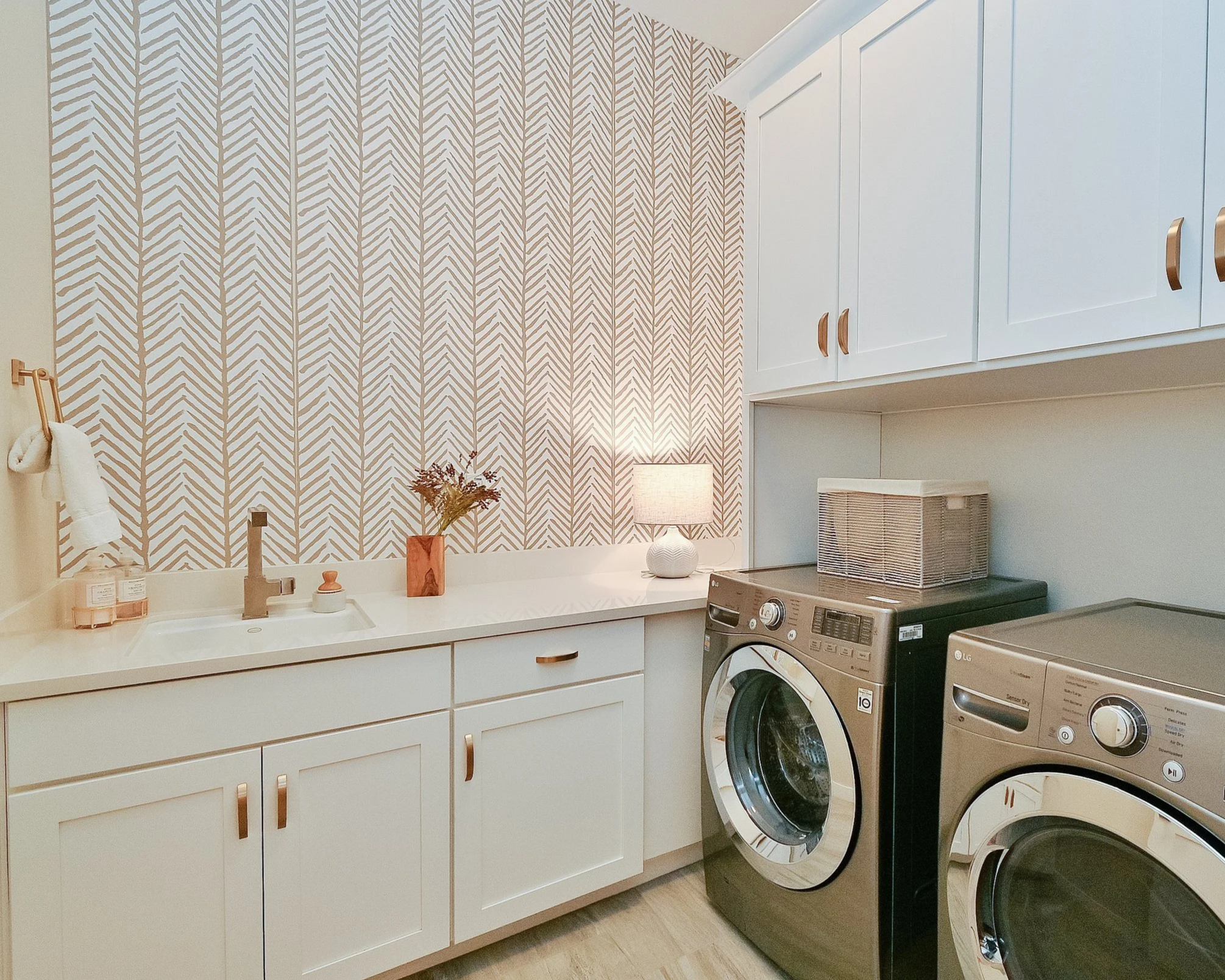 White laundry room with brass accents and striped wallpaper--Casa Limones interior design