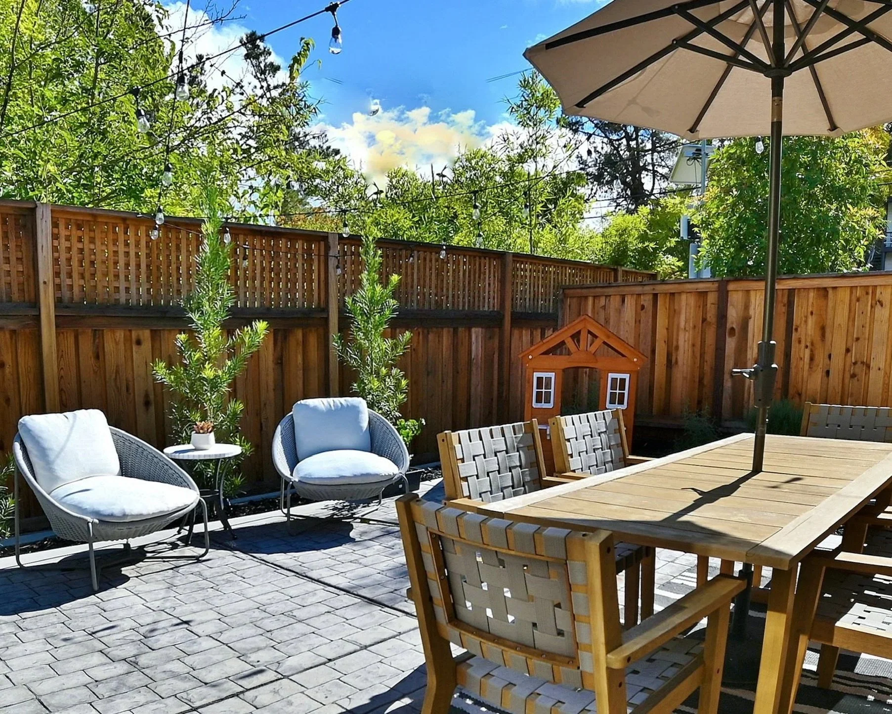 Backyard patio with outdoor dining table, lounge chairs, and playhouse--Casa Limones interior design