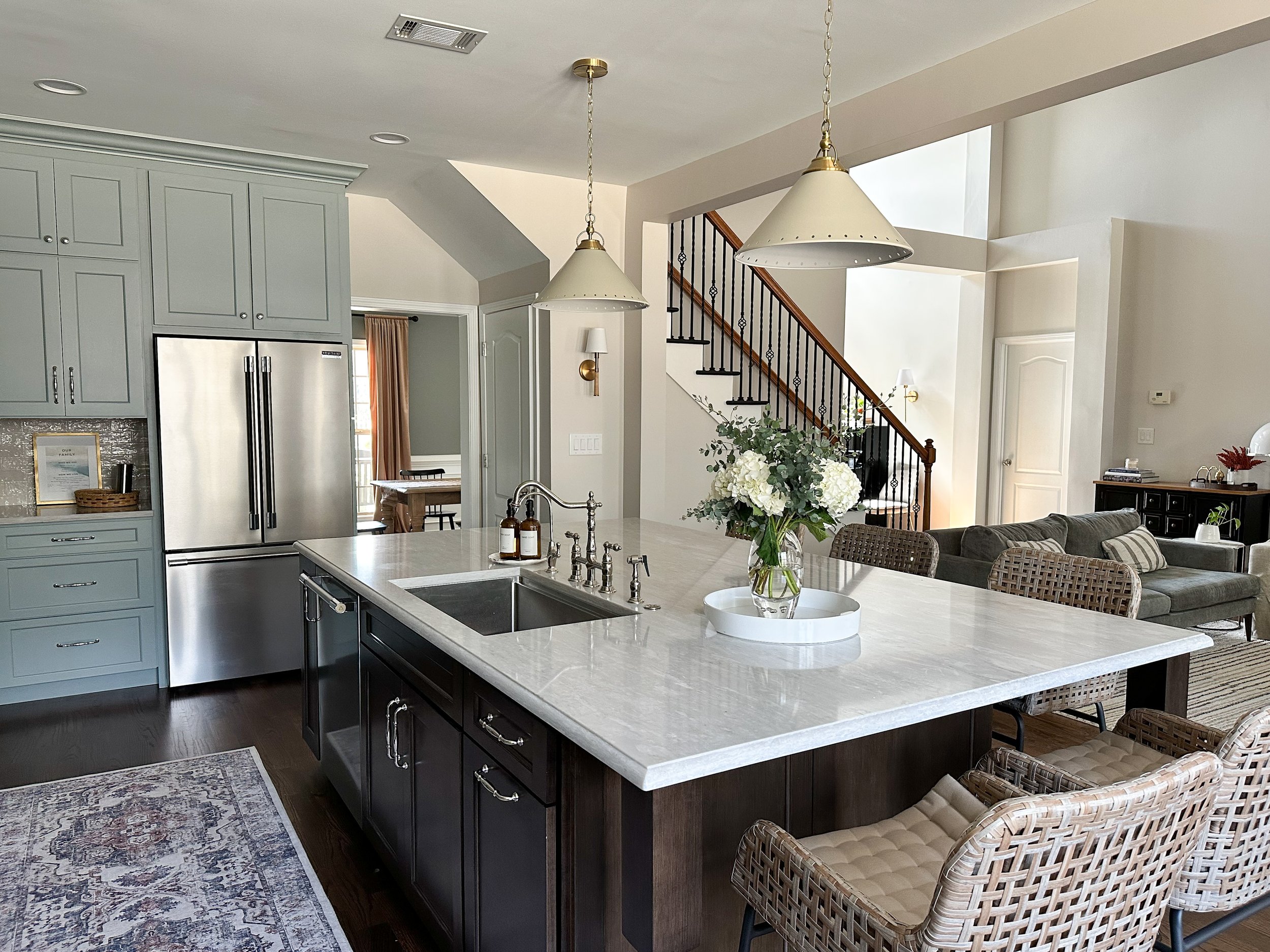 Light blue kitchen with white quartz countertops, walnut island, brass accents, polished nickel hardware, wicker counter stools, and vintage runner--Casa Limones interior design