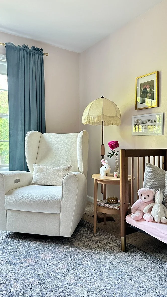 Girls' nursery bedroom with light pink walls, dark teal velvet drapes, walnut crib, ivory glider, vintage rug--Casa Limones interior design