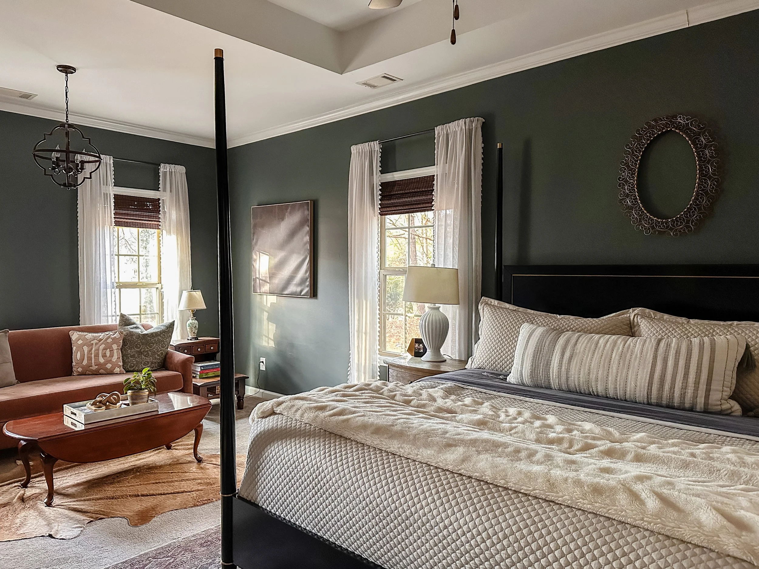 European primary bedroom with black four-poster bed, blush sofa, and bamboo window coverings--Casa Limones interior design