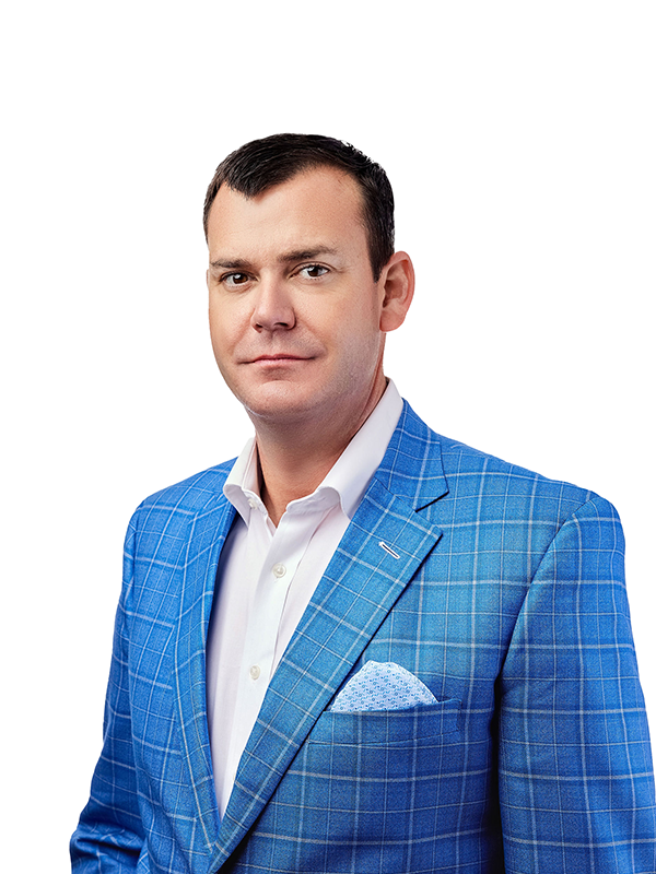 Man in a blue checkered suit with a white shirt, pocket square, standing against a white background.