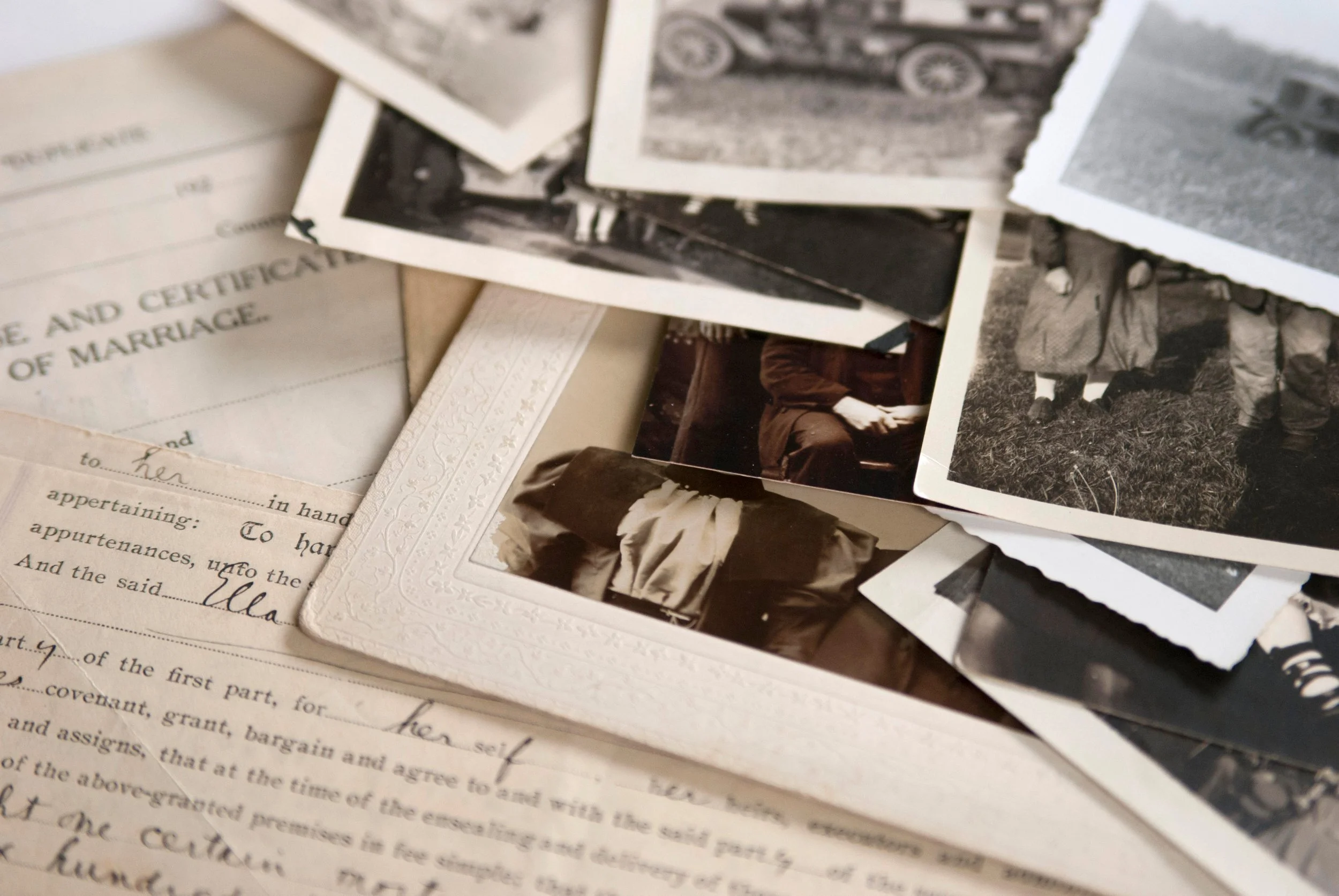 A collection of black-and-white photographs and a certificate of marriage in the background.