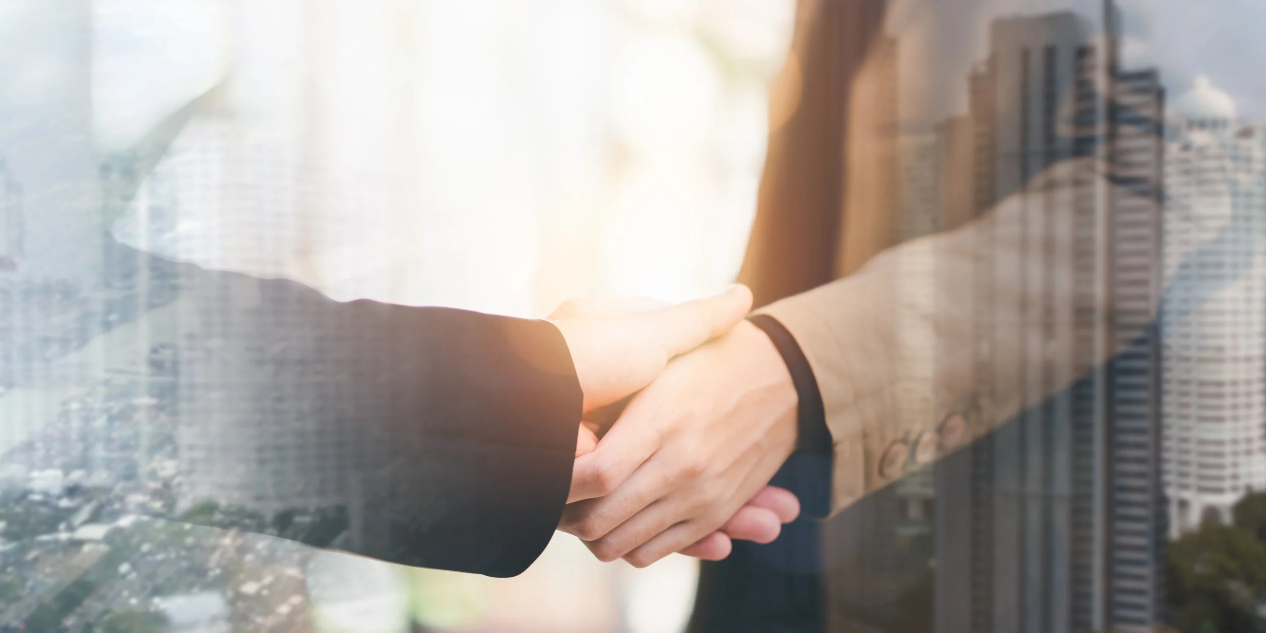 Two people shaking hands, with a city skyline reflected behind them.