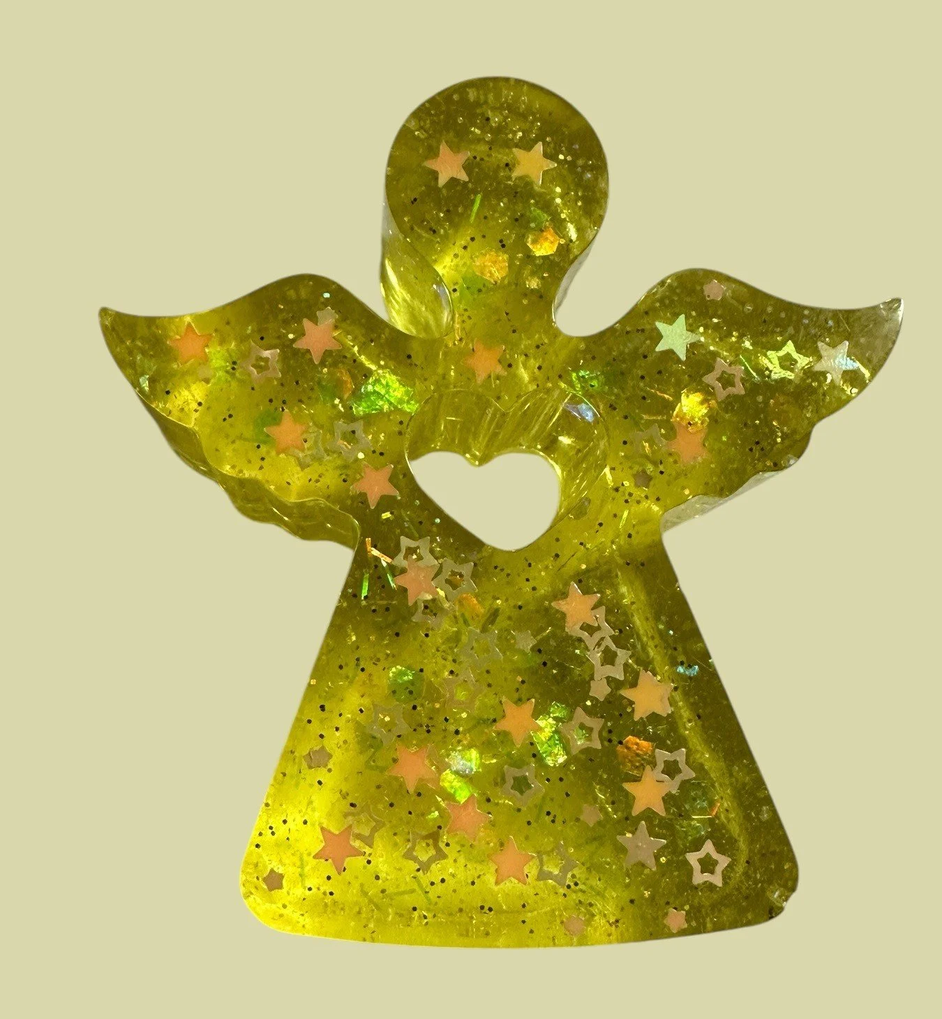 Yellow angel-shaped ornament with glitter and star-shaped confetti inside, featuring a heart cutout in the center.