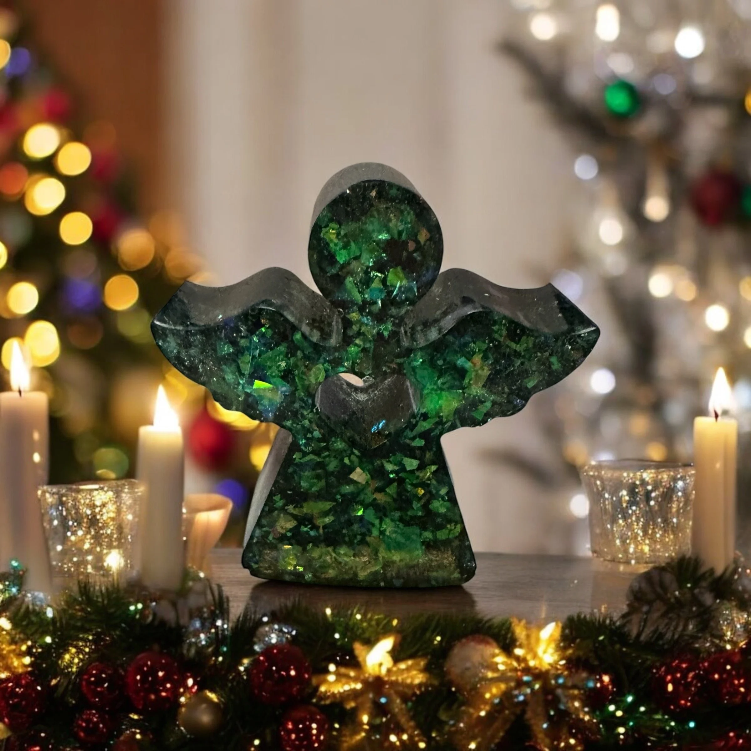 A decorative angel sculpture made of green and black marble, surrounded by Christmas candles and holiday decor, with a decorated Christmas tree in the background.