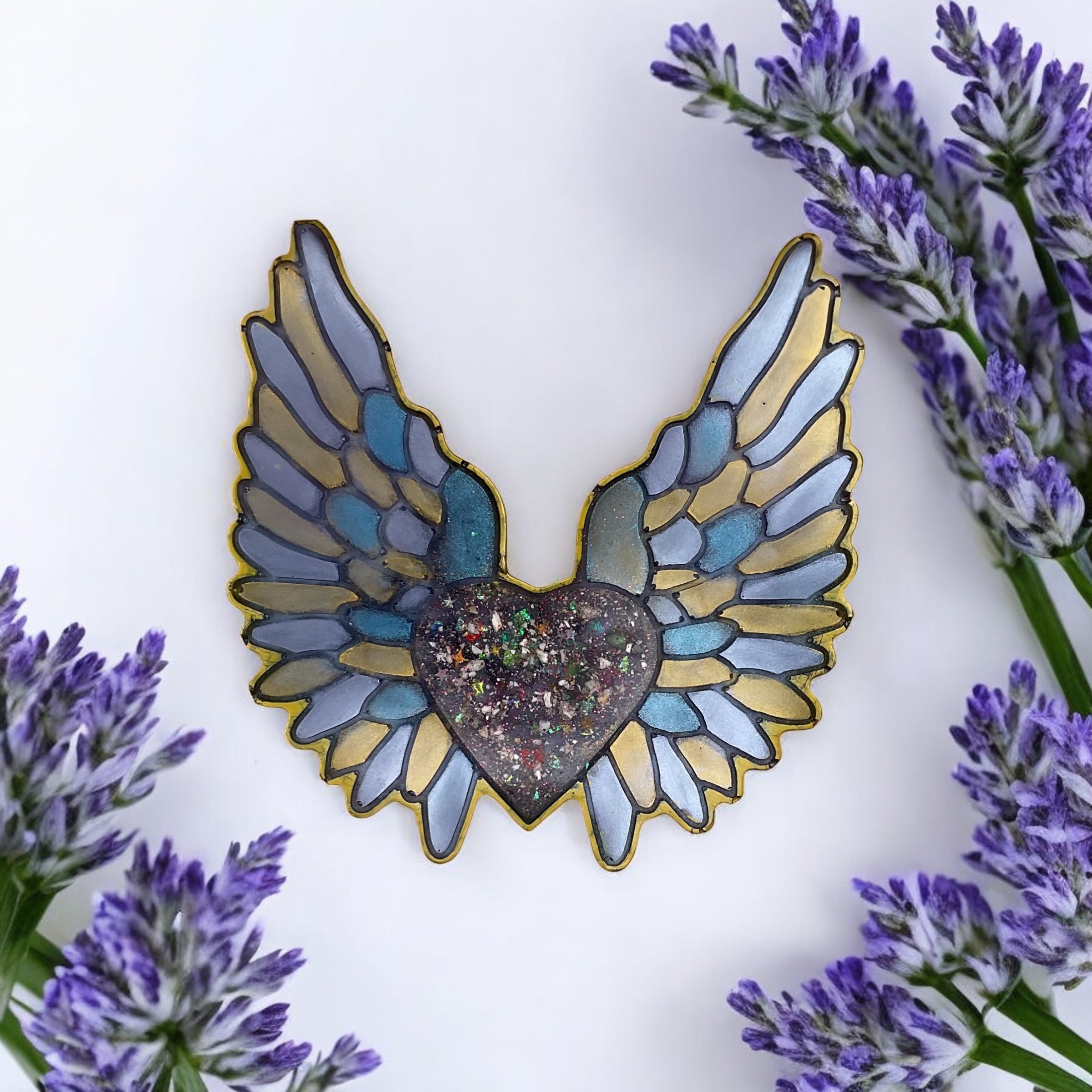 Colorful stained glass butterfly with outstretched wings, featuring a heart-shaped body and purple, blue, and gold hues, surrounded by sprigs of purple lavender flowers on a white background.