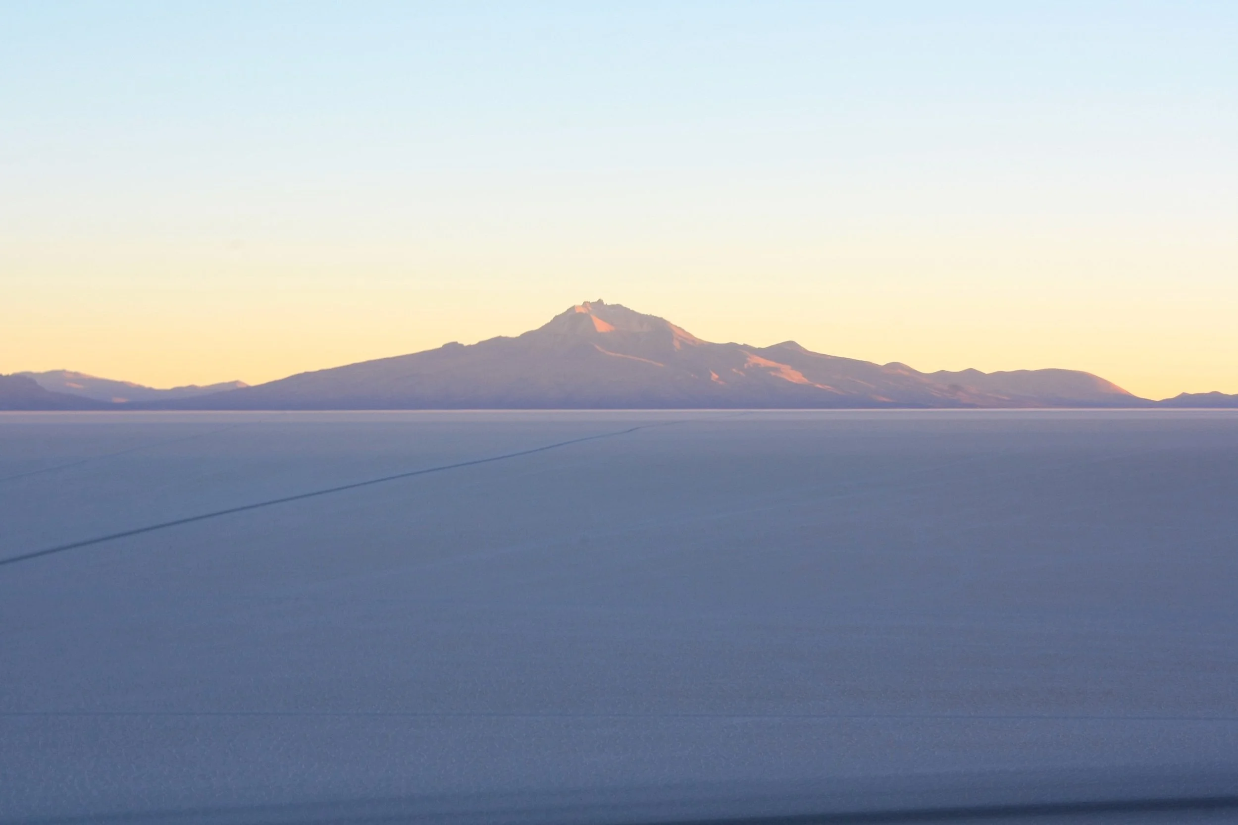 A snow-covered landscape with a distant mountain in the background, under a clear sky.