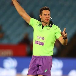 Referee Ben O'Keeffe, in a neon green shirt and purple shorts gesturing on a tennis court.