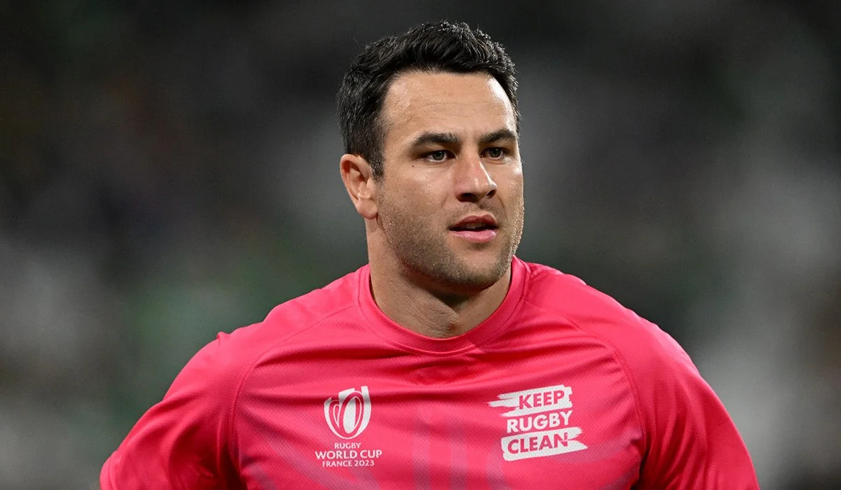 Ben O'Keeffe a rugby referee in a pink jersey, focused on the game, on a blurred background.