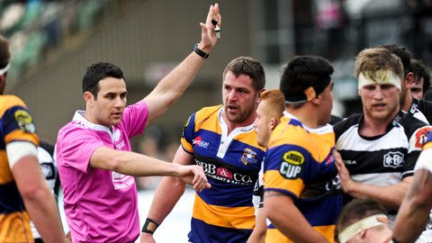 Referee Ben O'Keeffe showing a penalty signal to rugby players during a match.