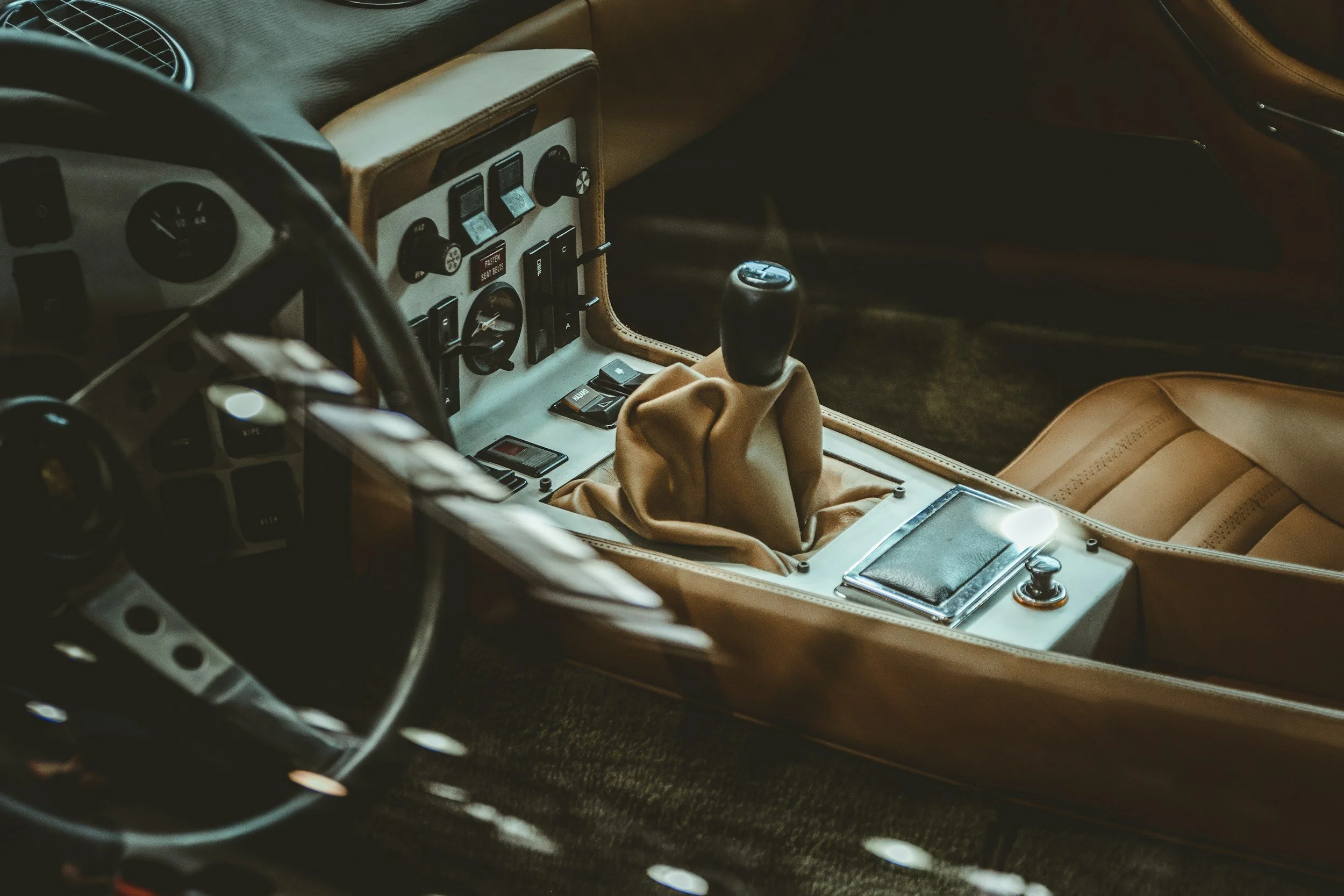 Interior of a vintage car focusing on the central console with a gear shift, control switches, and a small compartment.
