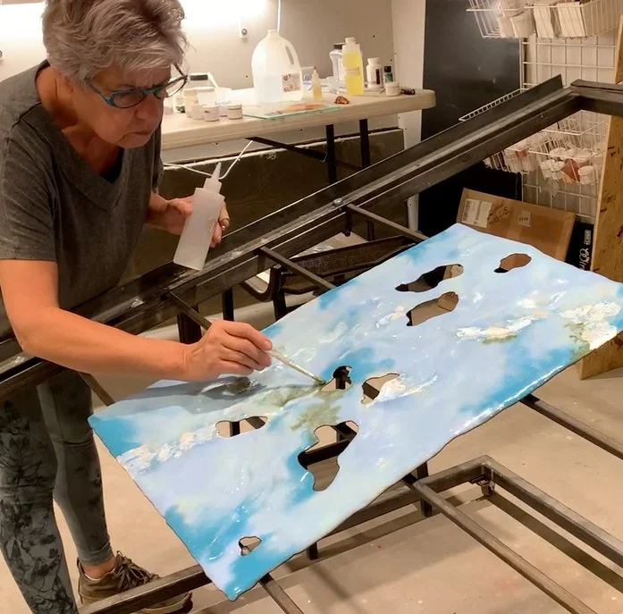 Diana Ahrens painting with vitreous enamel.  Piece is mounted in custom pivot table.