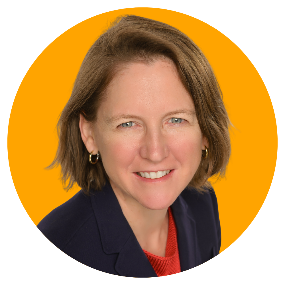 Professional headshot of a smiling woman with short brown hair, wearing a dark blazer and red top, set against a yellow background.