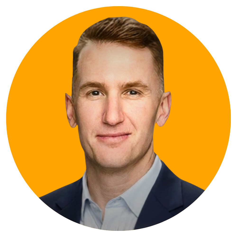 A professional headshot of a man with short, neatly styled hair wearing a dark blazer and a light-colored shirt in front of an orange background.