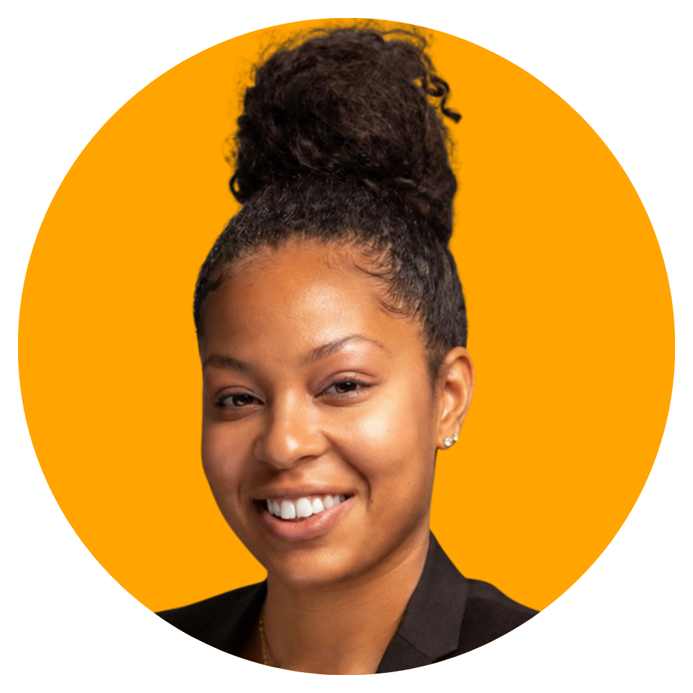 A smiling woman with dark curly hair styled in a high bun, wearing a black blazer and small earrings, against a bright orange background.