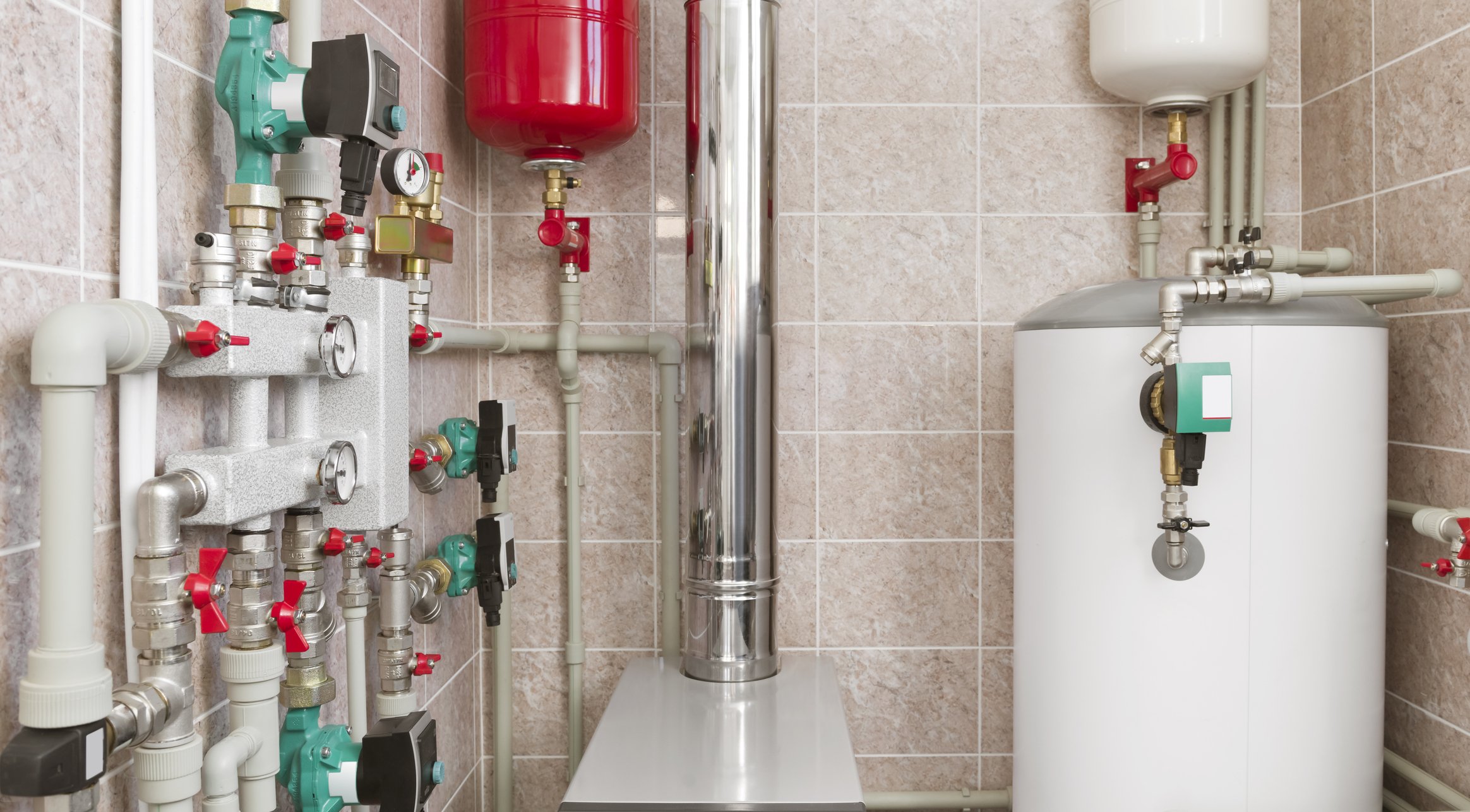 A plumbing room with various pipes, gauges, and valves connected to a tank and a white water heater.