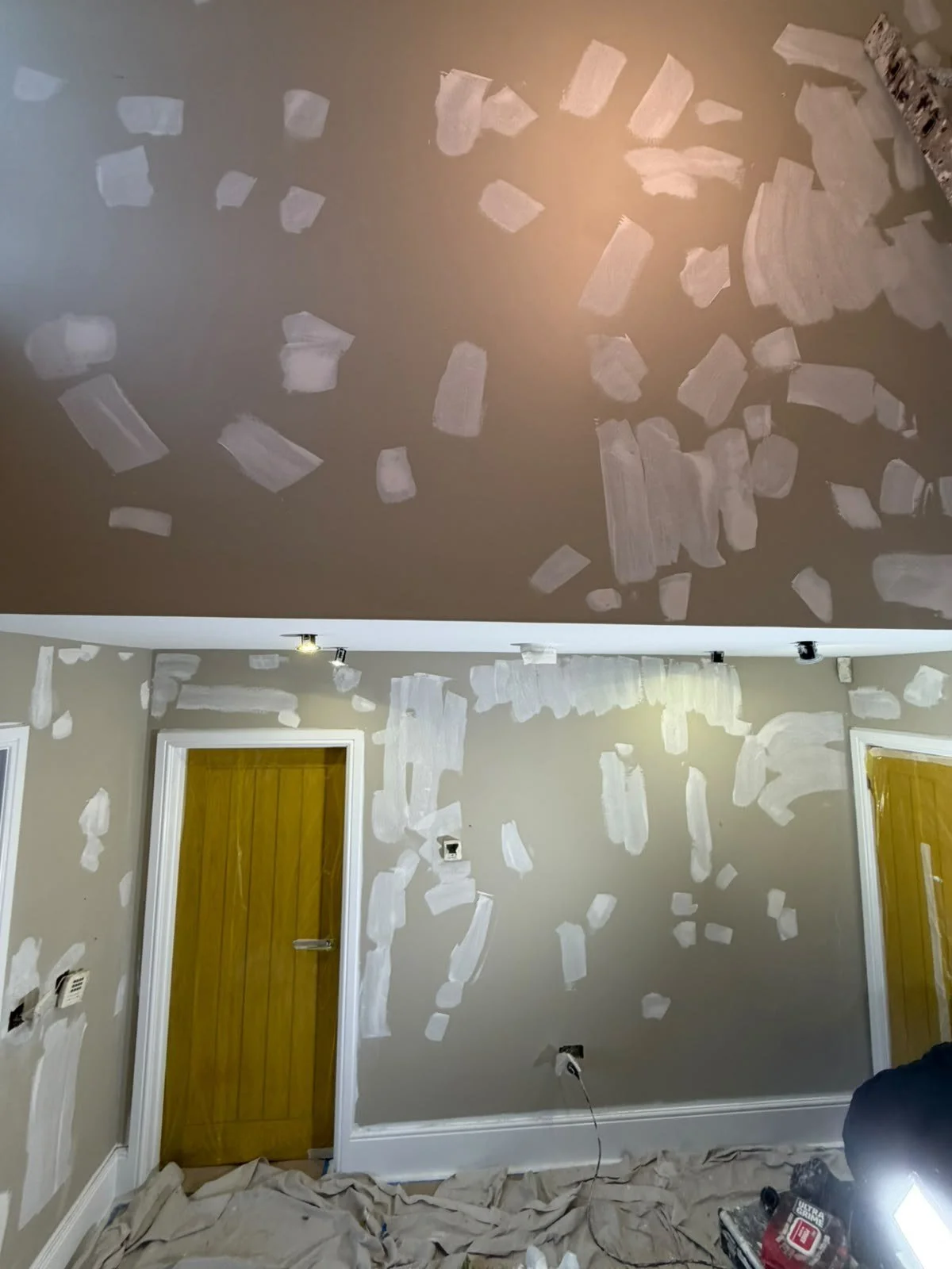  Ceiling and walls with filler patches applied before painting, with dust sheets on the floor 
