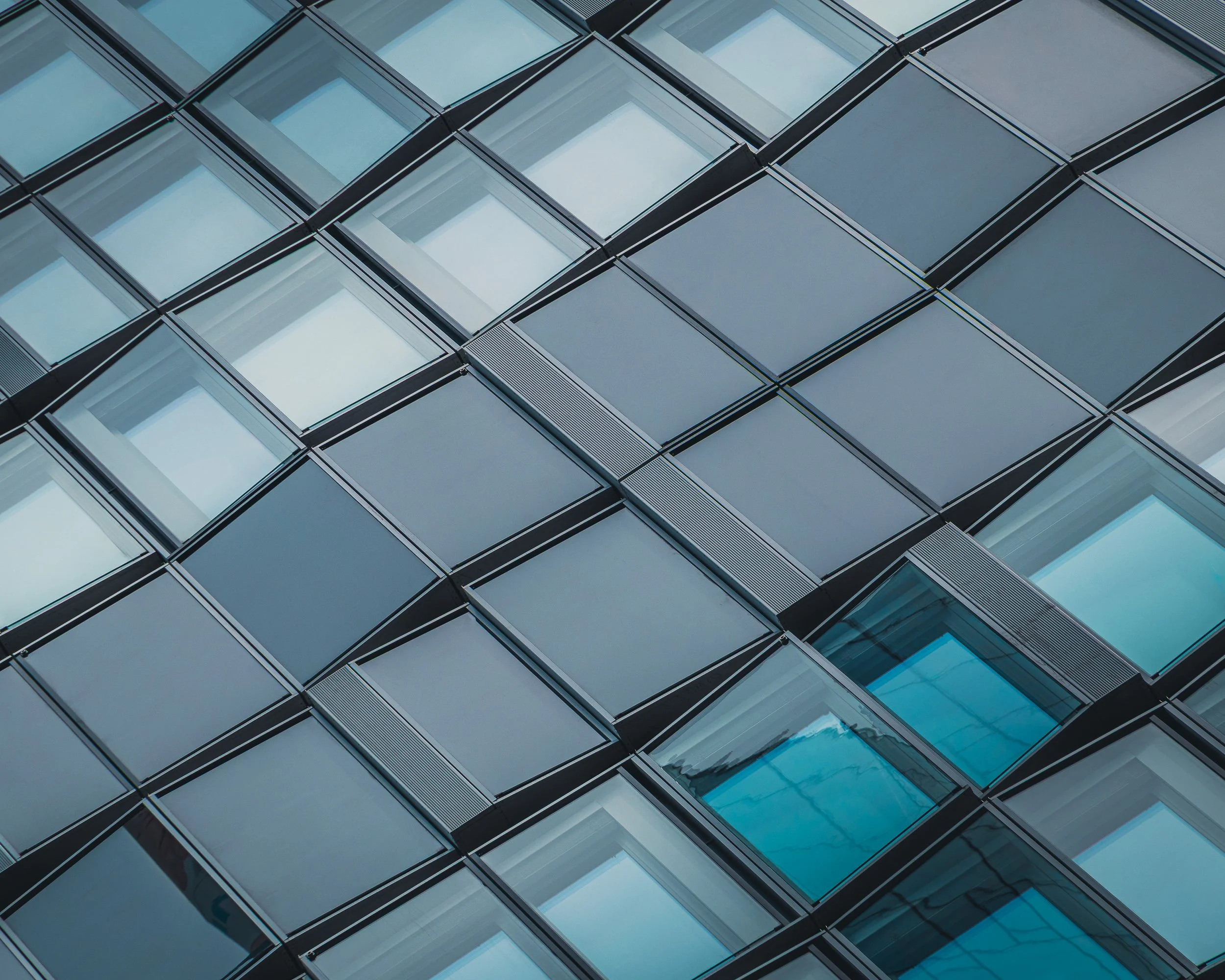 Diagonal grid of glass windows with one turquoise section breaking the pattern