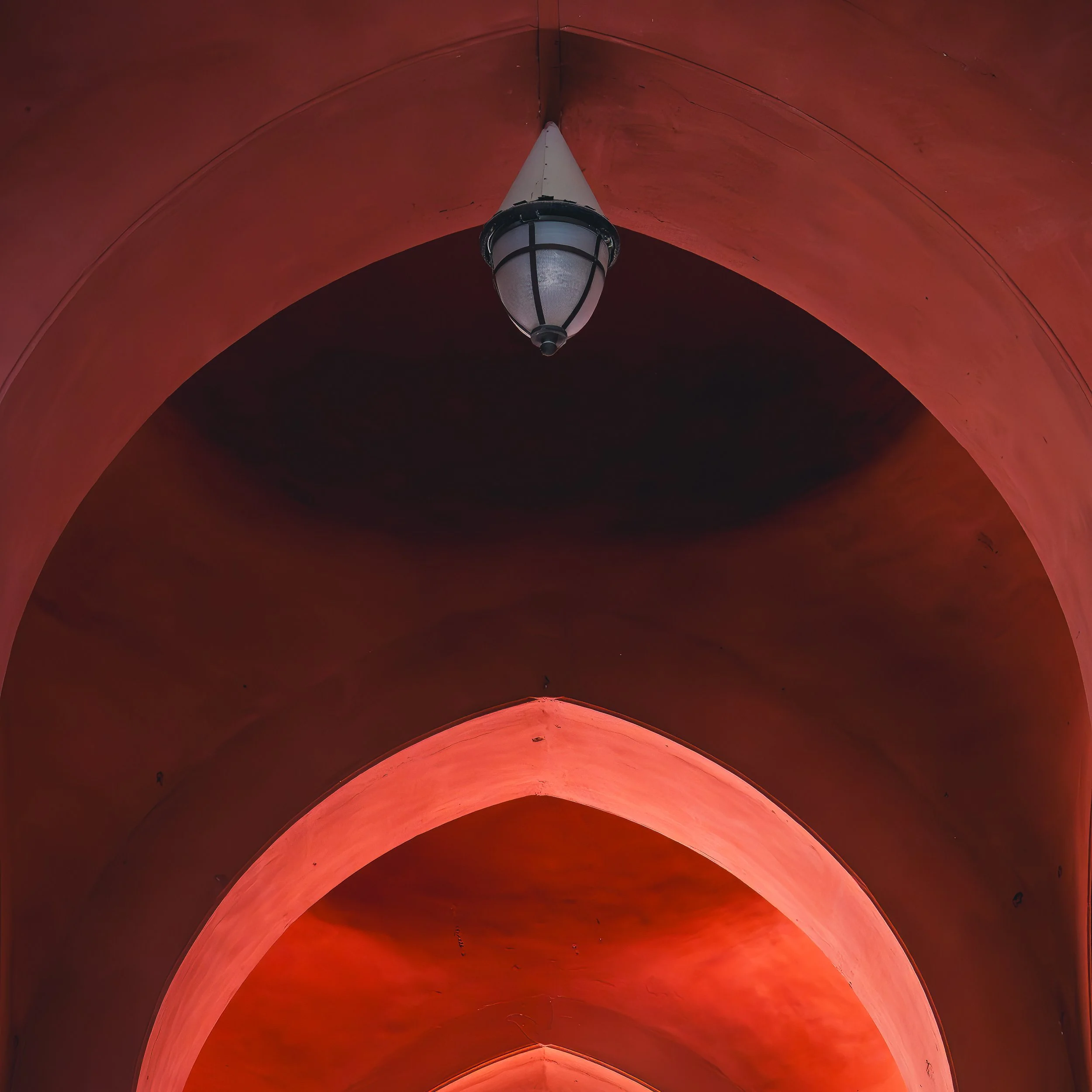 Repeating red arches with a hanging lantern inside a palace in Bikaner