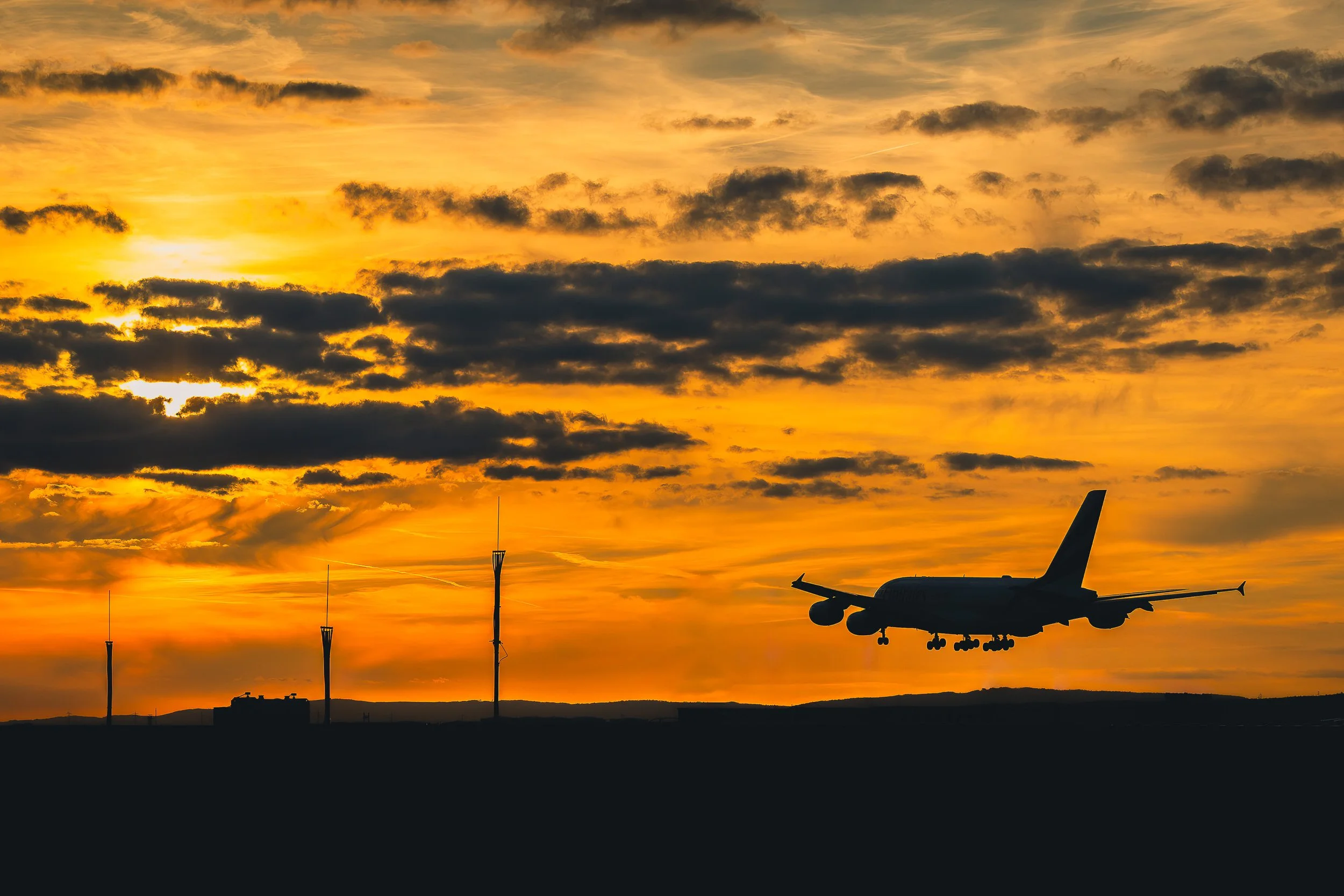 Airliner approaching Frankfurt Airport at sunset beneath an orange sky