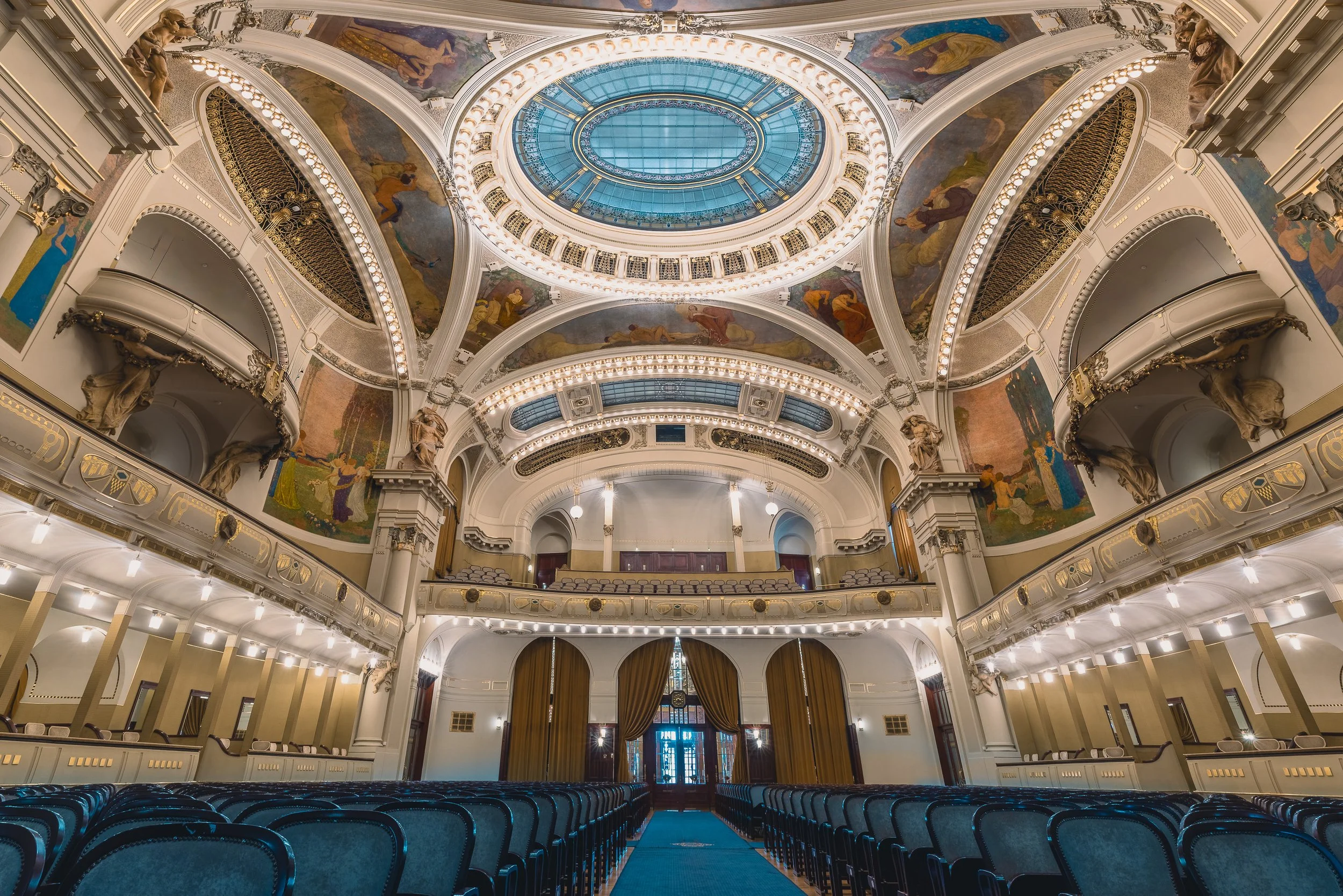 Grand Art Nouveau hall inside Prague's Municipal House with curved balconies and a glass ceiling