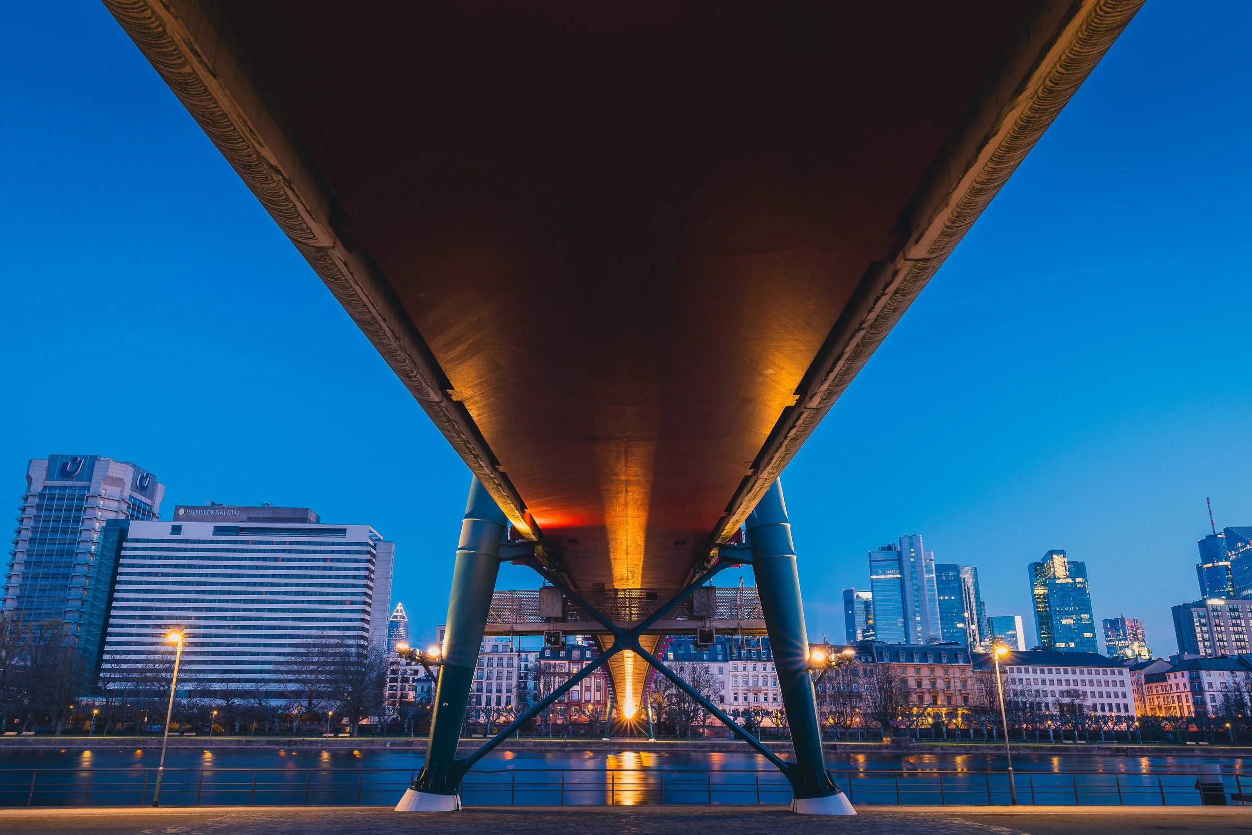 Frankfurt skyline at blue hour framed beneath Holbeinsteg