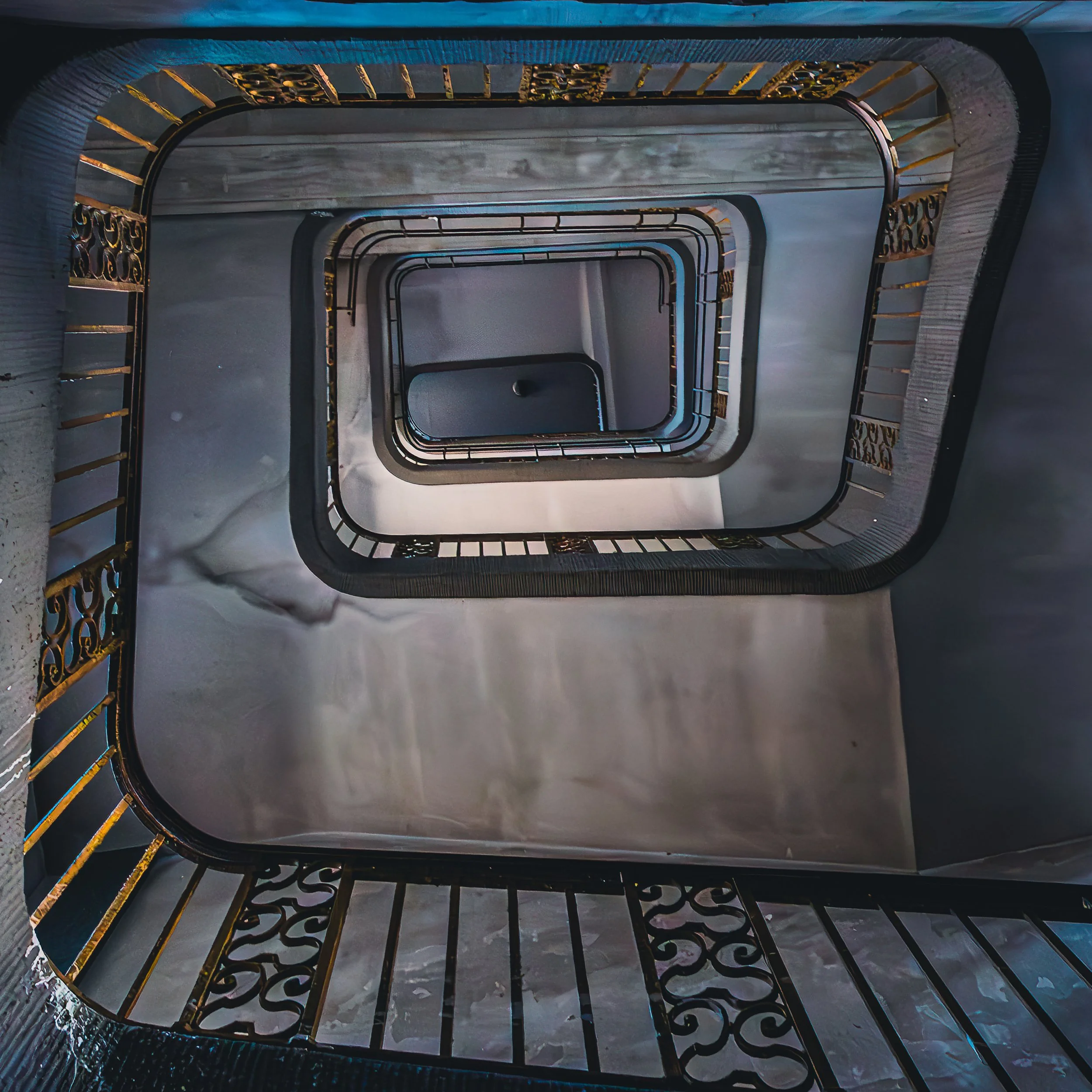 Square stairwell spiraling downward through repeating dark railings